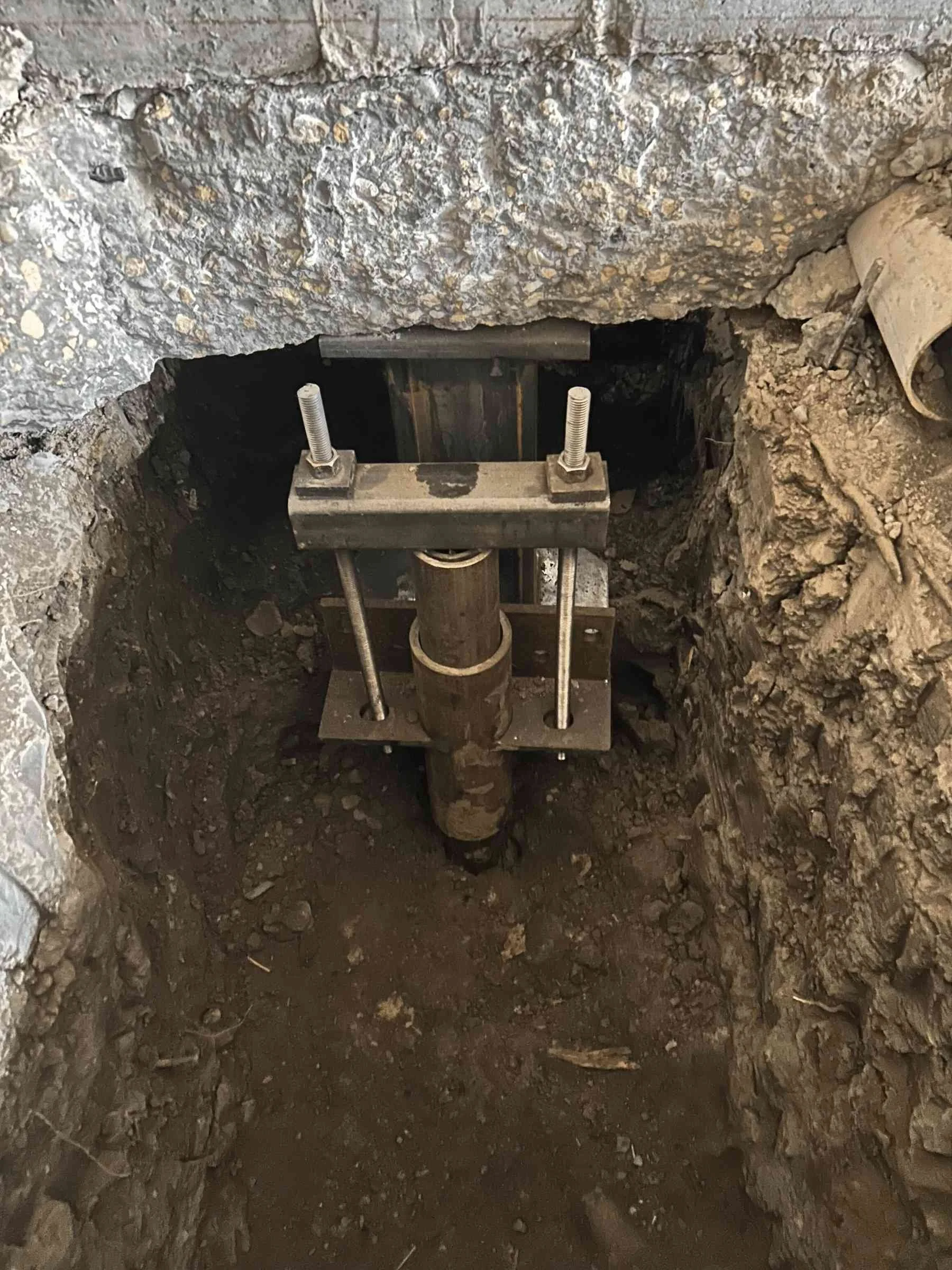 Construction site showing a support structure for a pipe in a deep excavated hole.