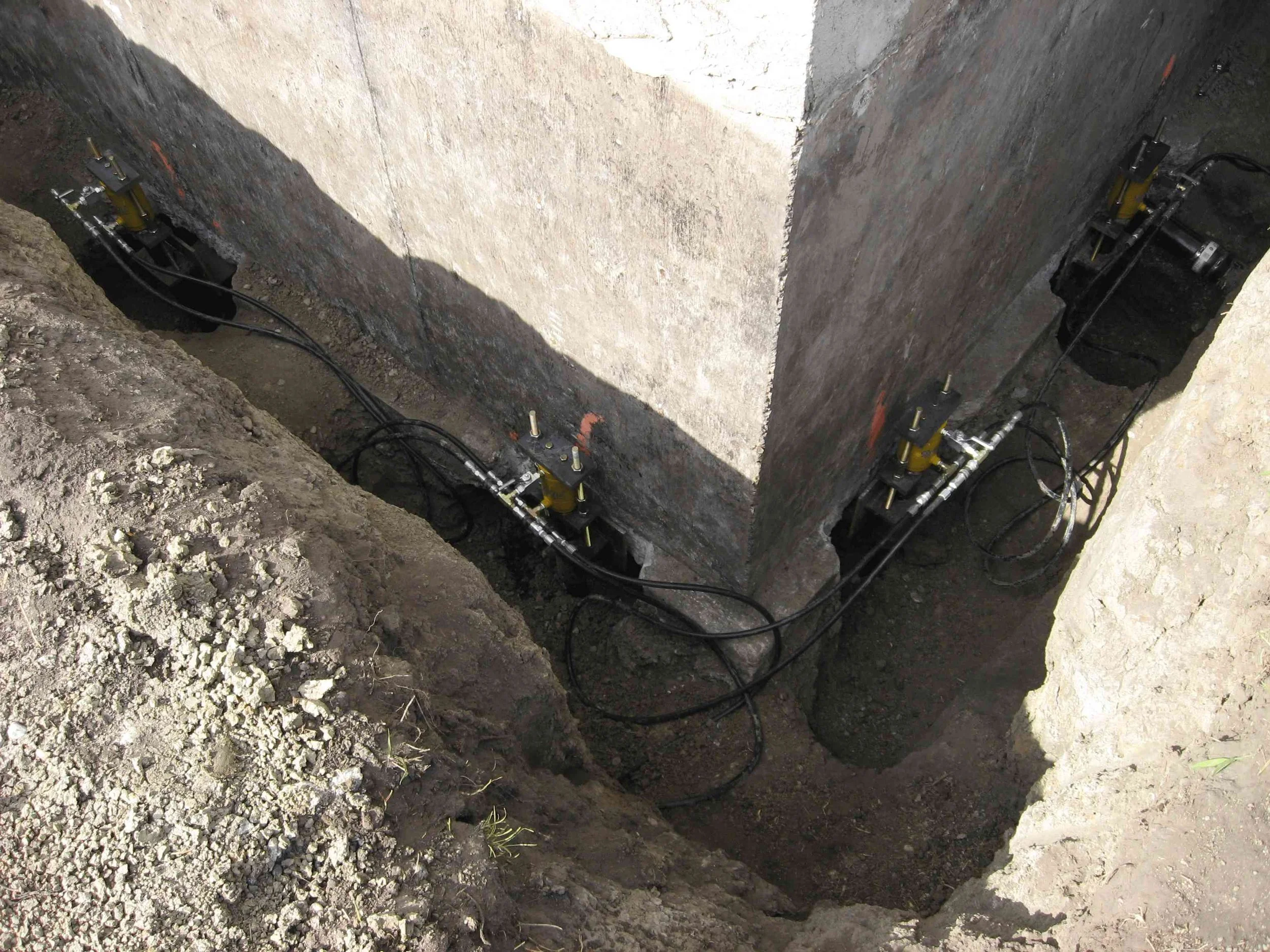 Pier system with hydraulic lines connected beneath the foundation during underpinning work.