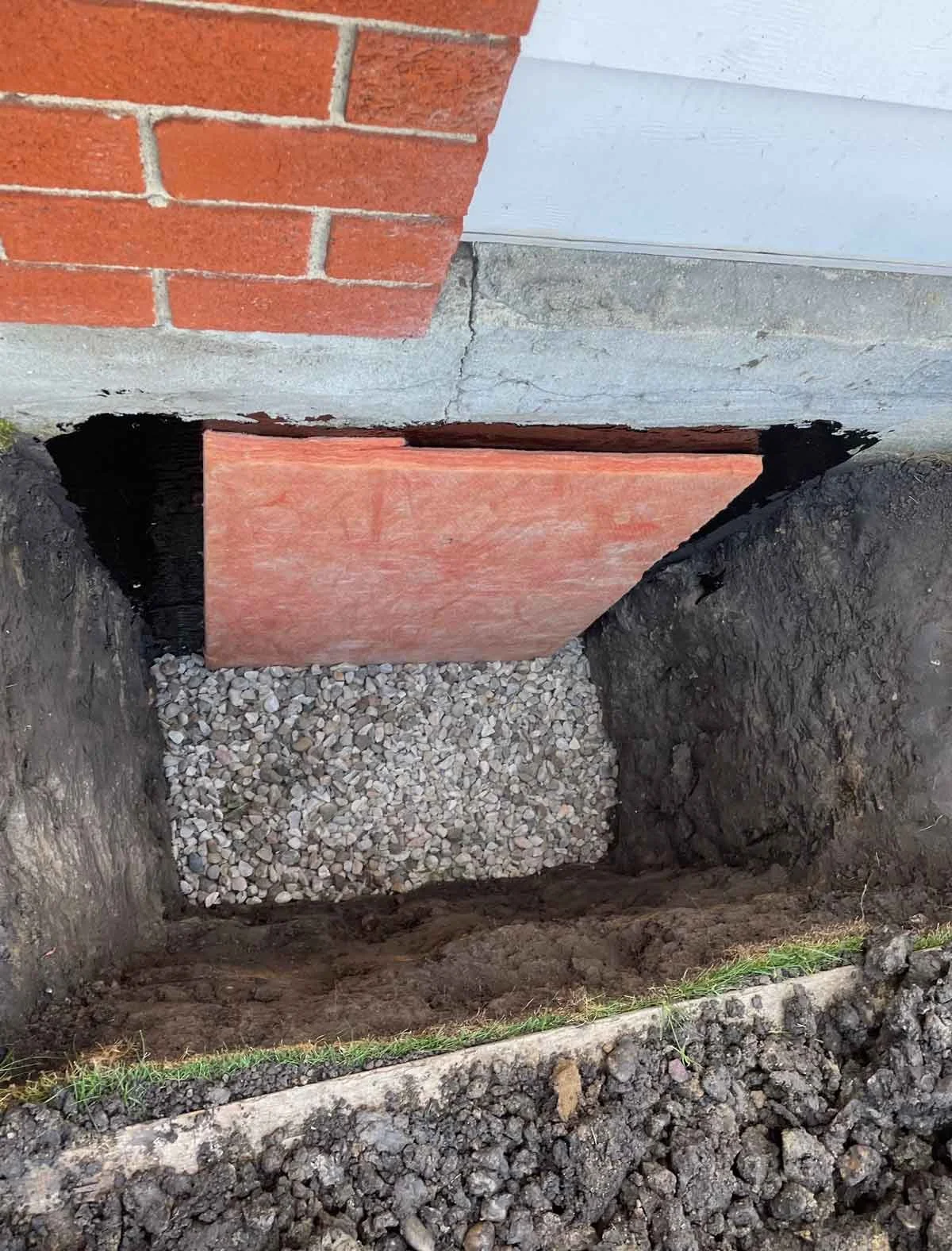 Applying foundation board over crack and covering weeping tile.