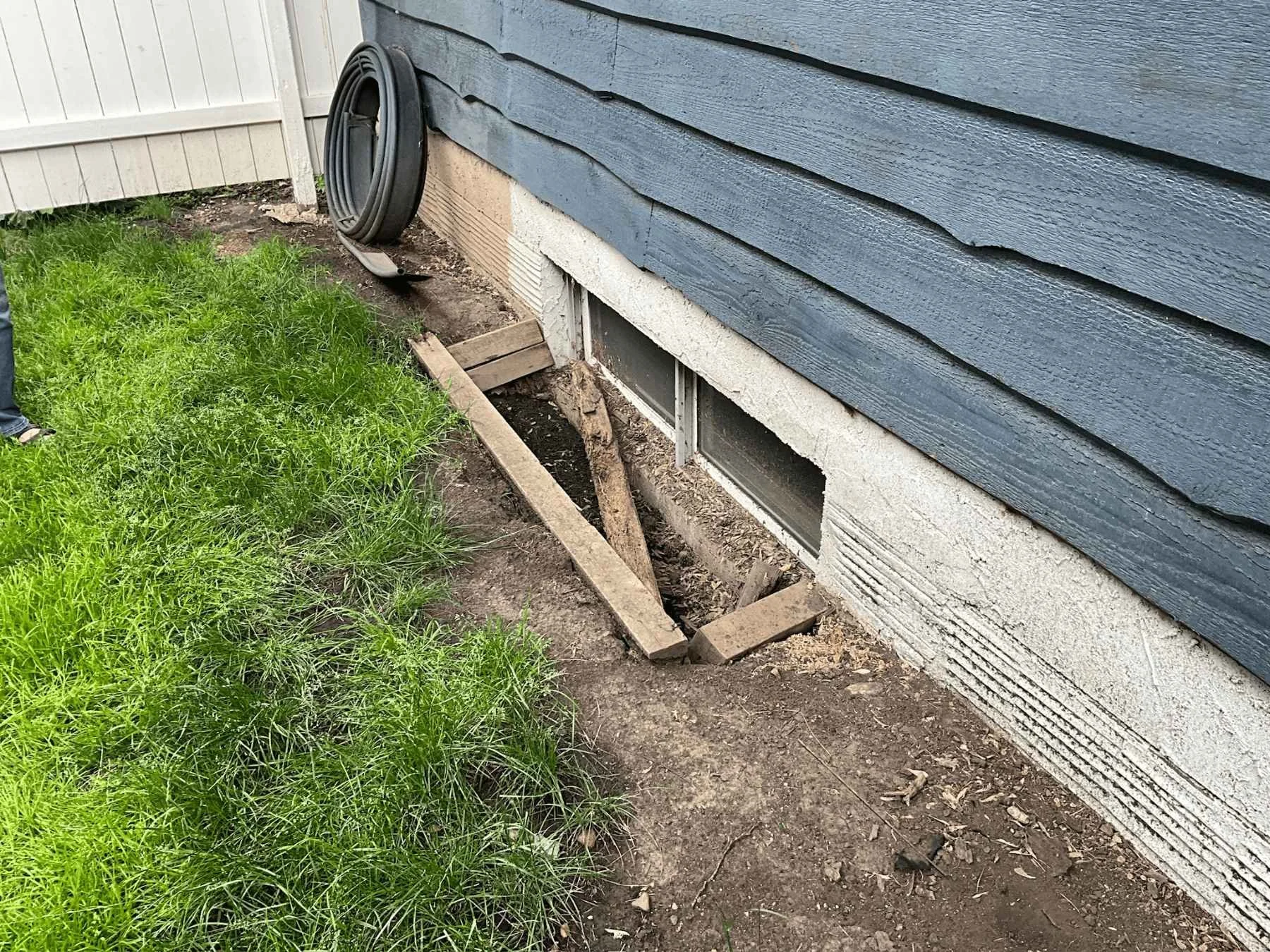 Collapsed window well with damaged surround, showing signs of deterioration that requires replacement.