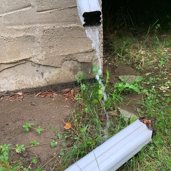 Downspout actively discharging rainwater away from the foundation to prevent water pooling.