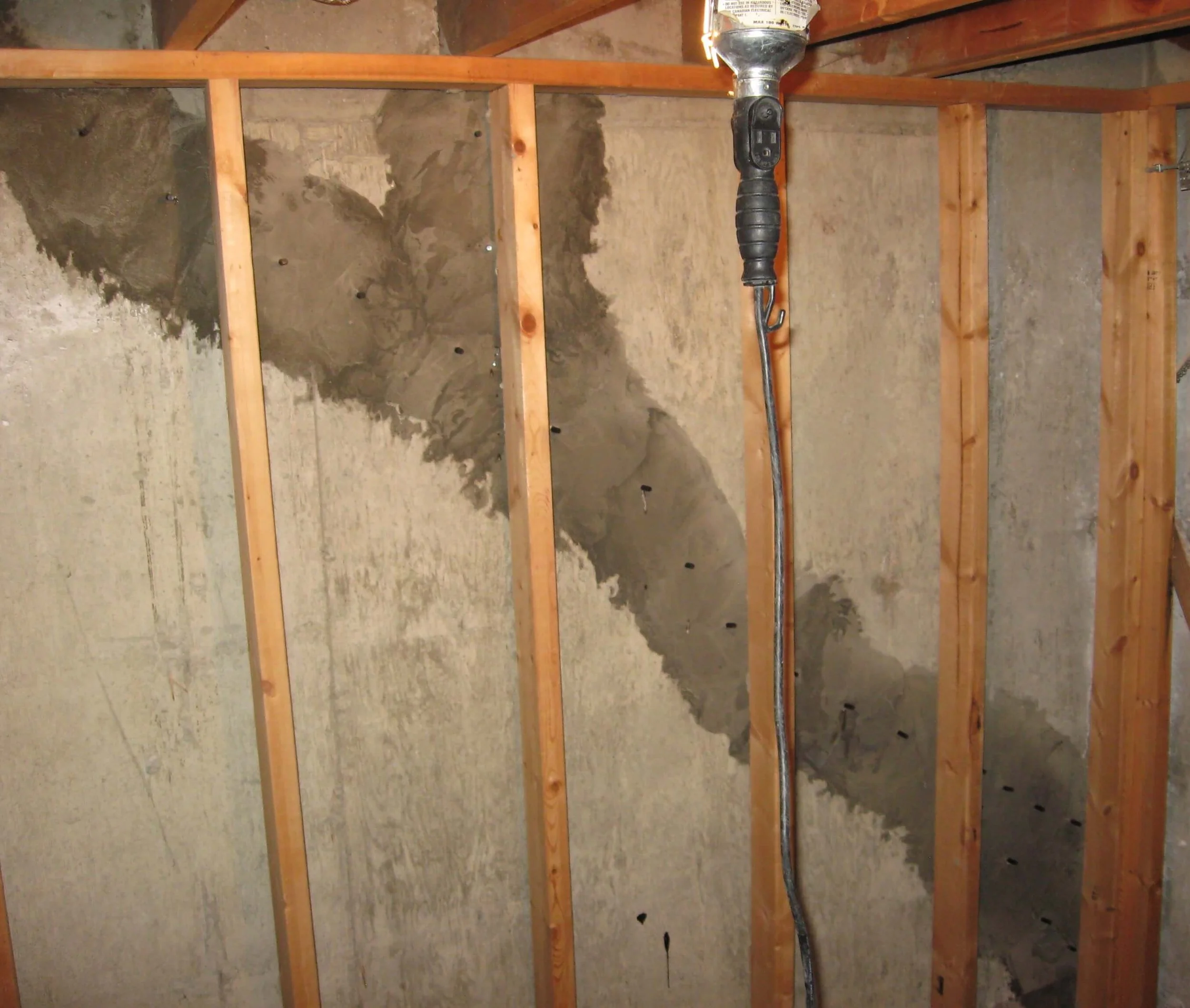 Interior of a room with exposed wooden framing, partially finished drywall, and an electric space heater hanging from the ceiling.