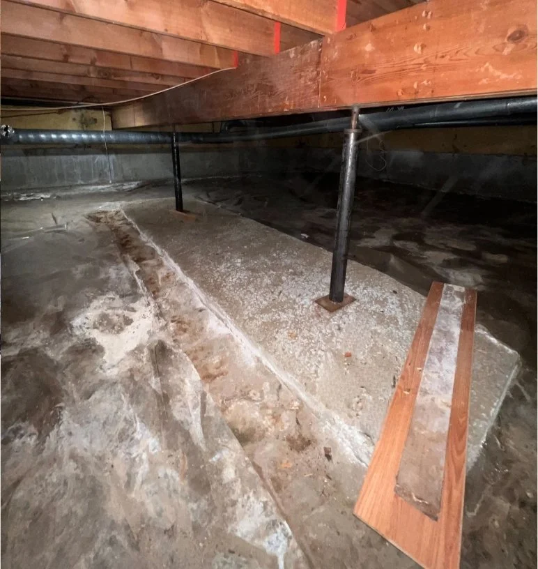 Steel telepost supporting a basement beam with excavation around the base for pad installation.