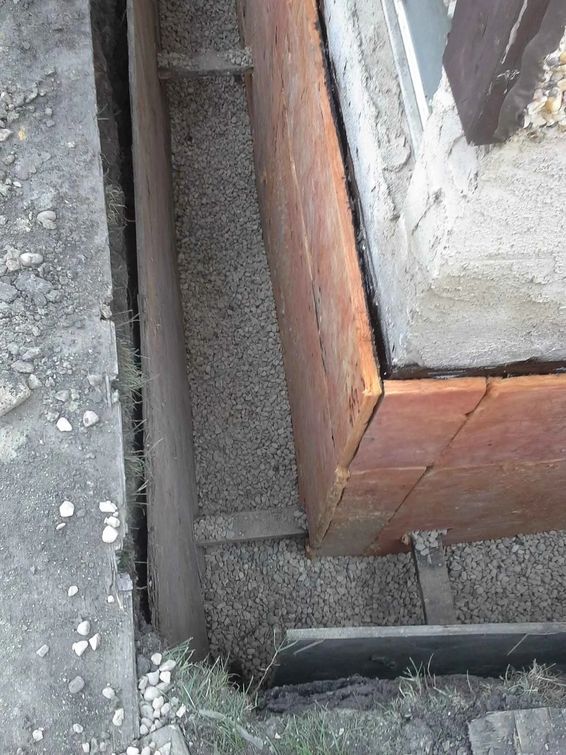 Completed interior weeping tile system with gravel drainage channel along basement foundation corner.