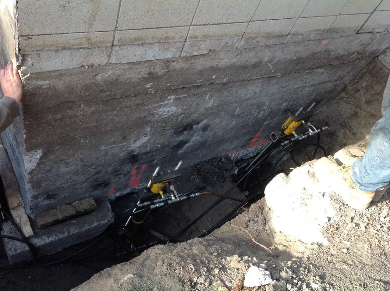 Two underpinning brackets installed beneath the footing to stabilize and lift a foundation.