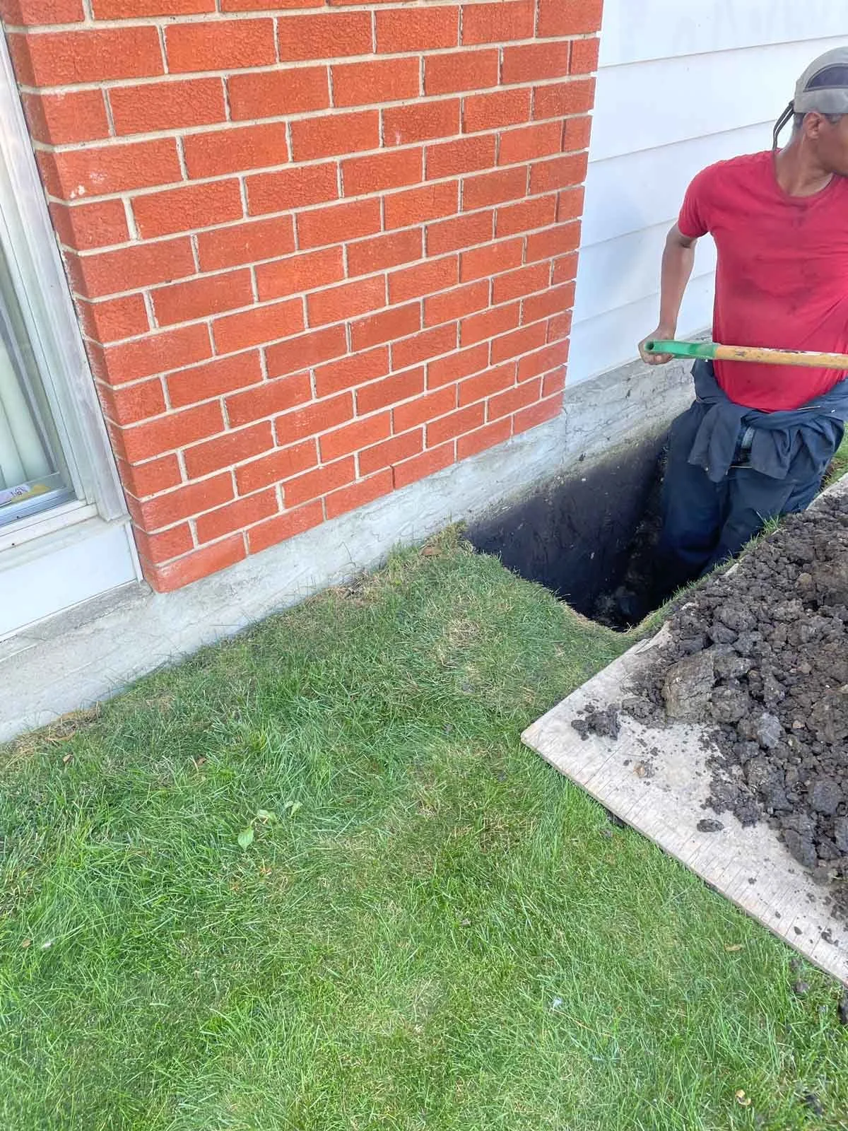 Excavating foundation to expose full crack for repair on brick home.