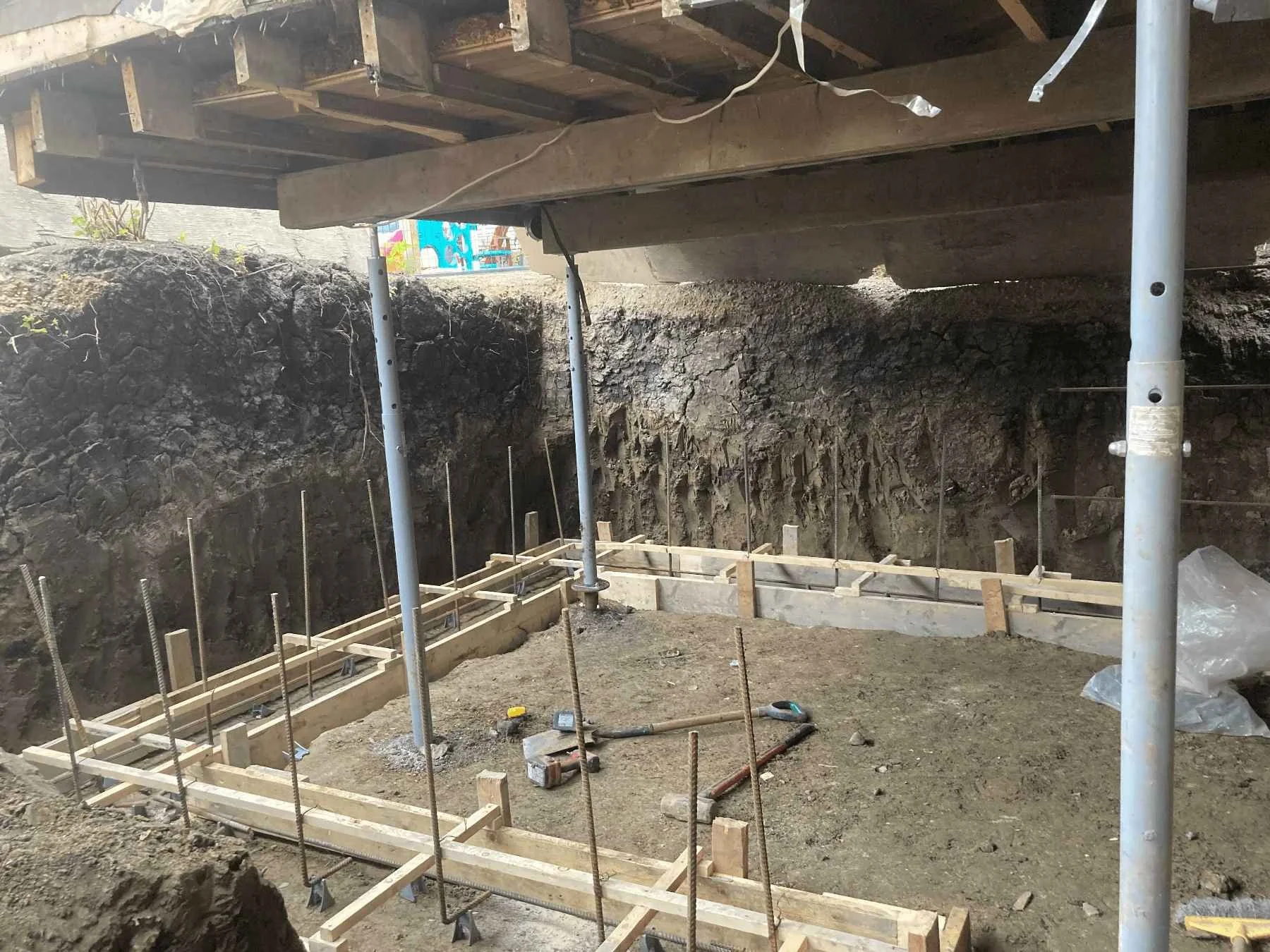 Foundation replacement in progress with temporary supports holding the home while new footings are poured.