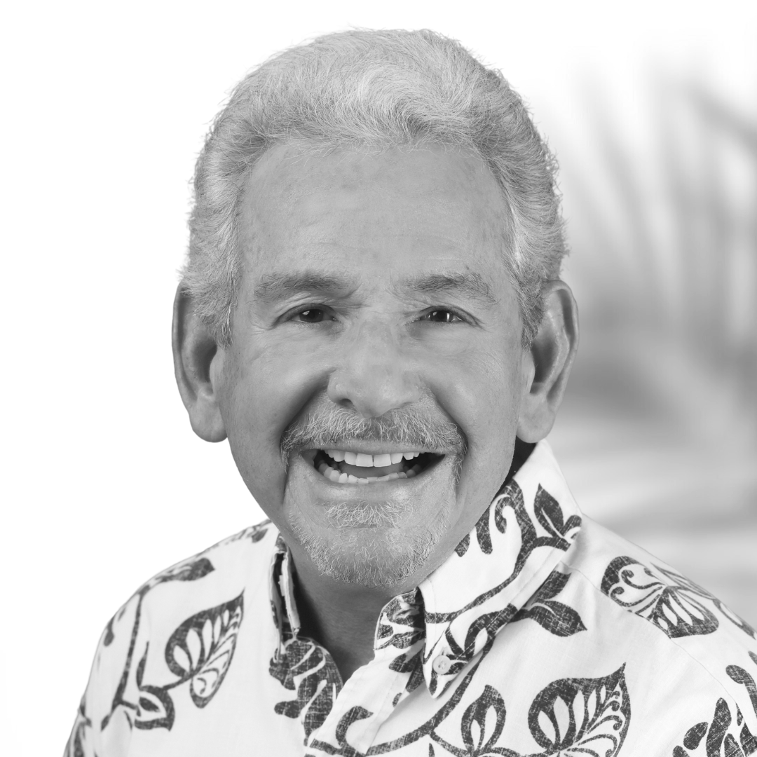 Black and white portrait of a smiling older man with gray hair, beard, wearing a Hawaiian shirt with a butterfly pattern.