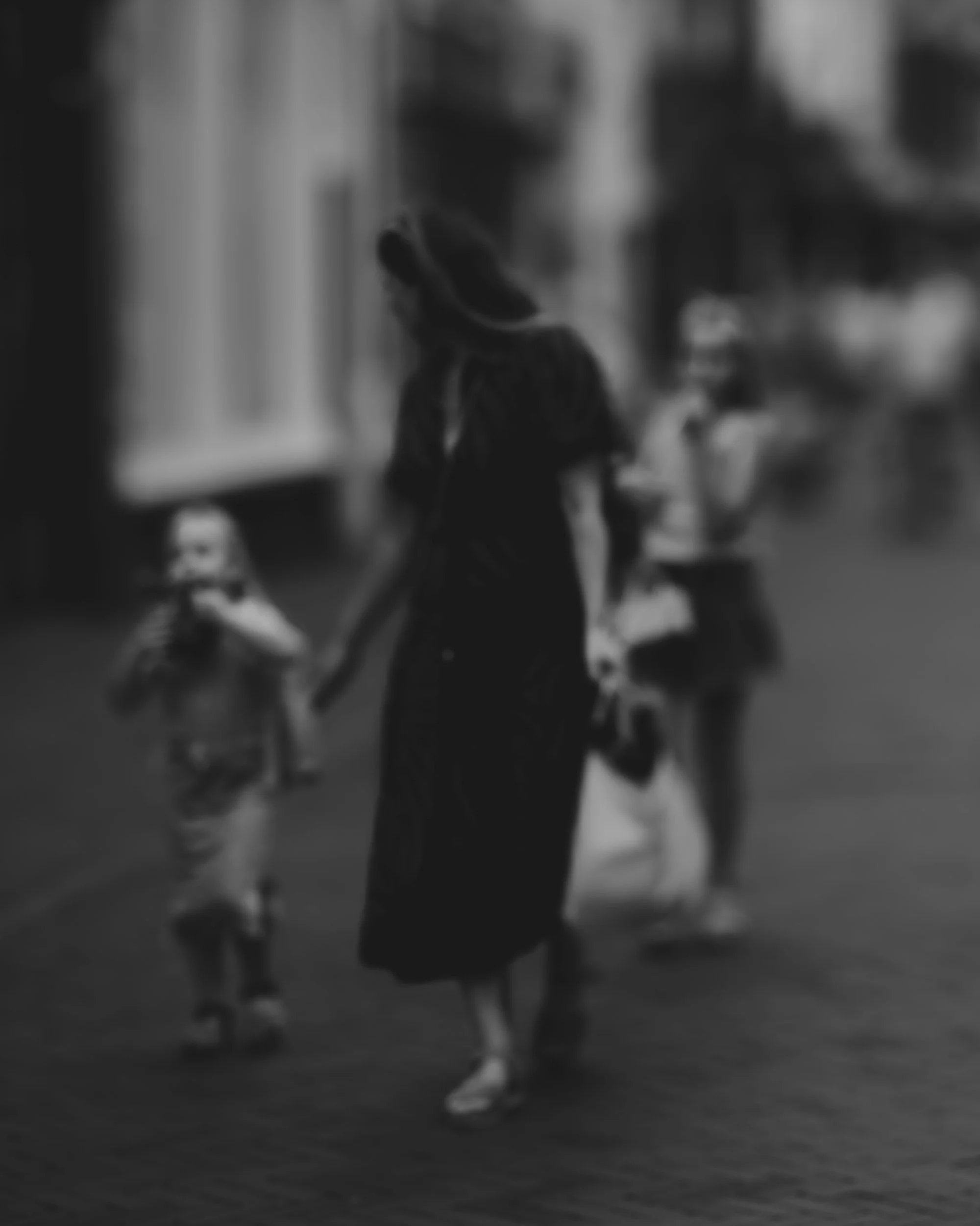 A woman walking with children in an urban setting, black and white photo