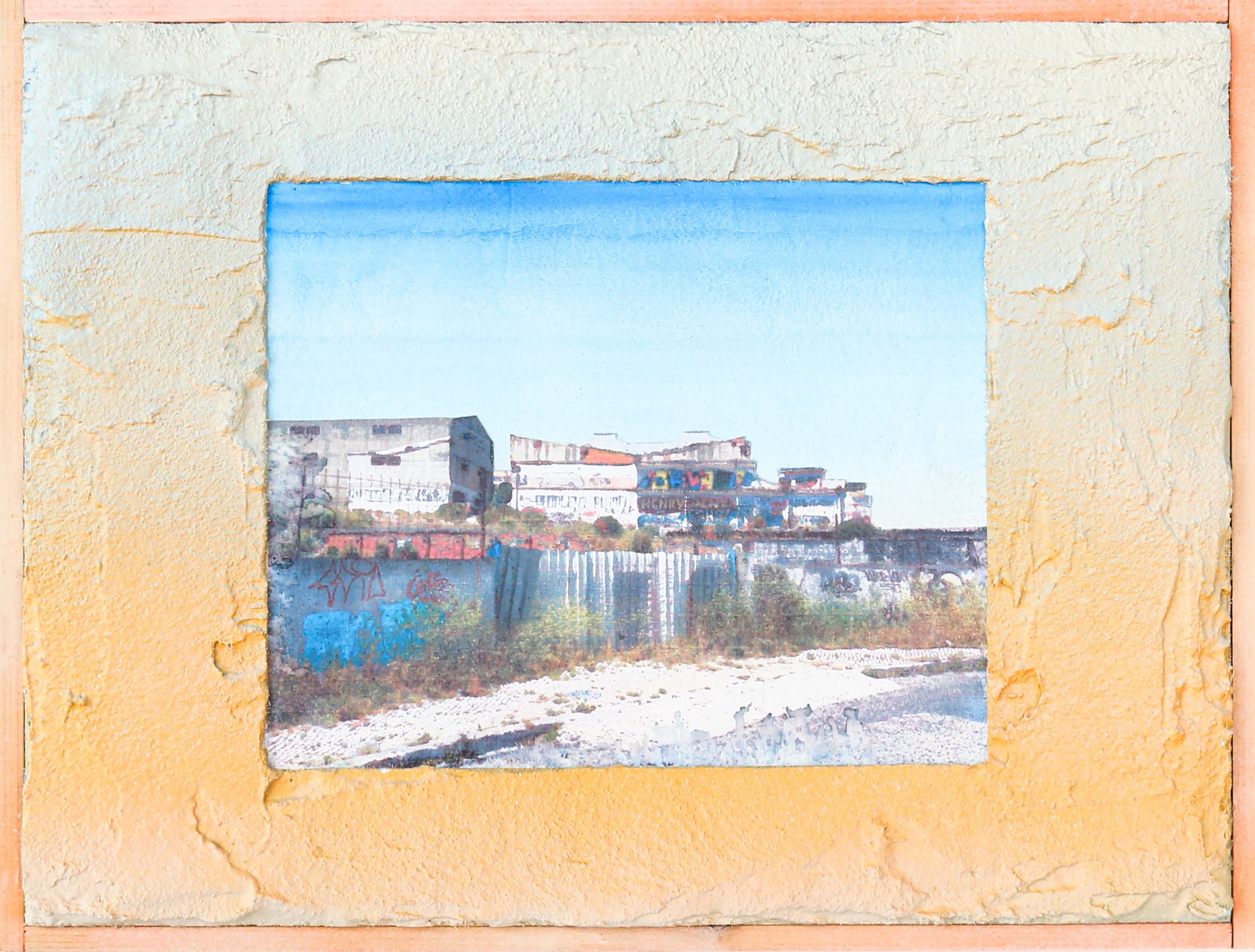 Photograph of buildings and graffiti seen through a rectangular cutout in a yellow textured wall.