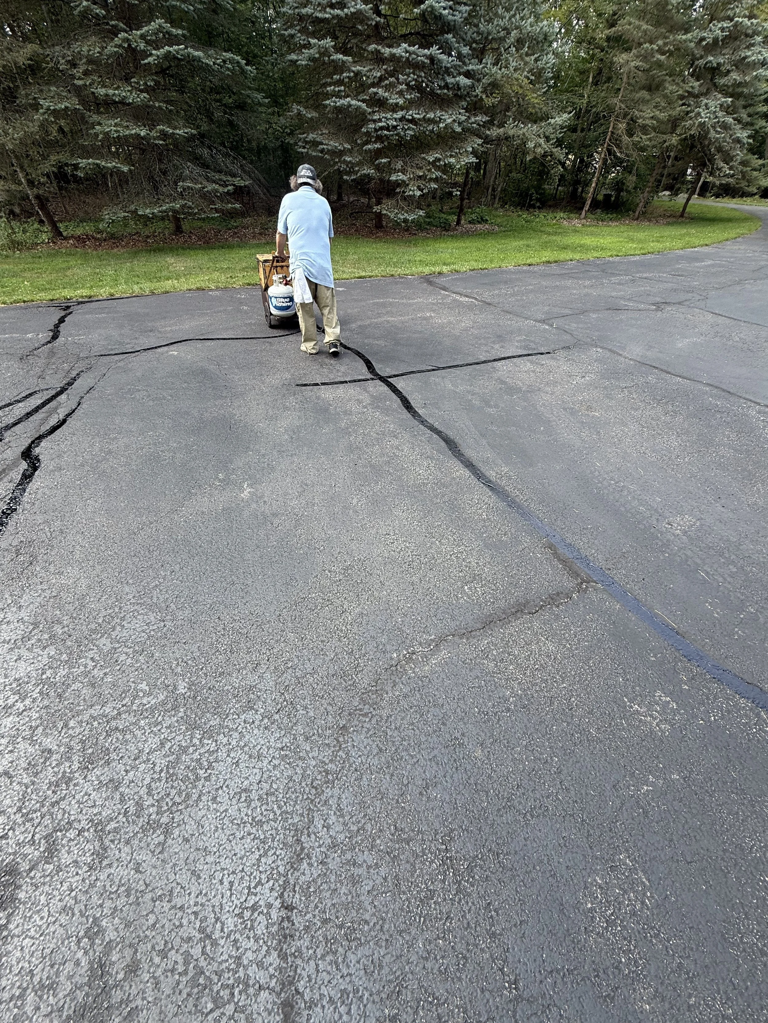 Sealcoat and hot crack filling worker fixing driveway