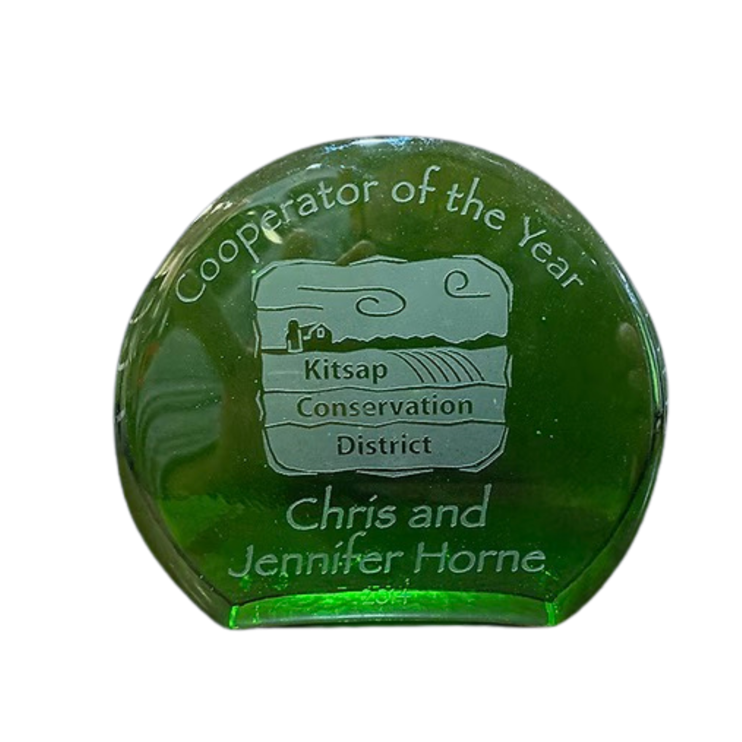Green glass award with engraved text that reads 'Cooperator of the Year' and 'Chris and Jennifer Horne,' featuring a landscape with a barn and fields, for Kitsap Conservation District.