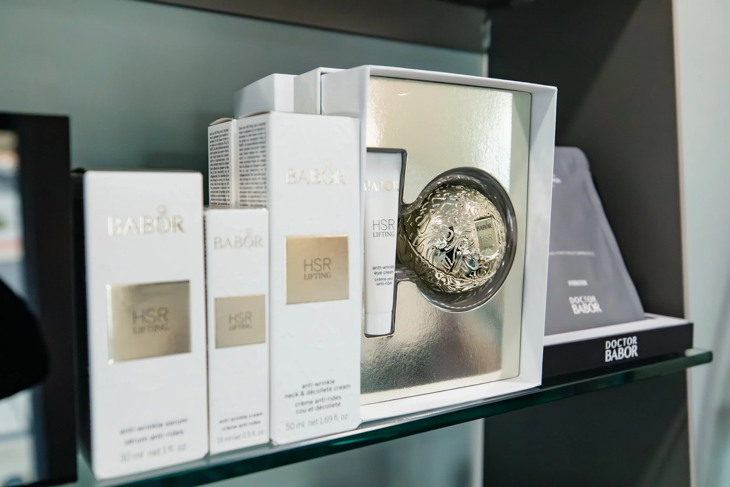 Display of skincare products, including Babor HSR Lifting anti-wrinkle eye cream, on a glass shelf.