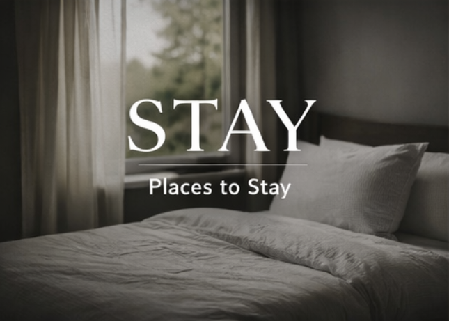A neatly made bed in a hotel room with a window, curtains, and a headboard, overlaid with the words 'STAY' and 'Places to Stay'.