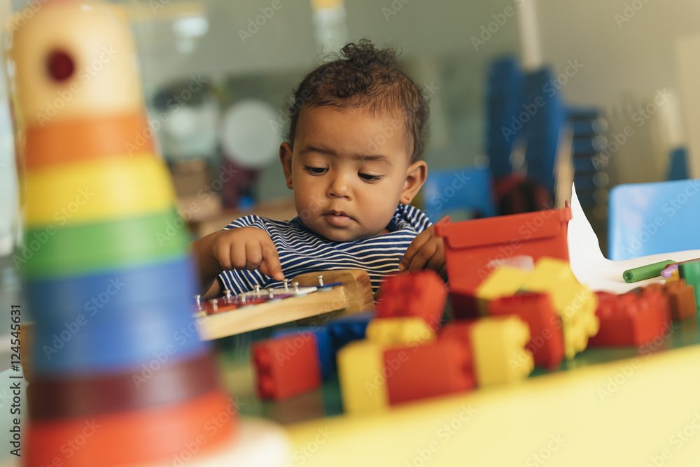 Young child playing with stacking toys and blocks, participating in hands-on childcare activities at an event.