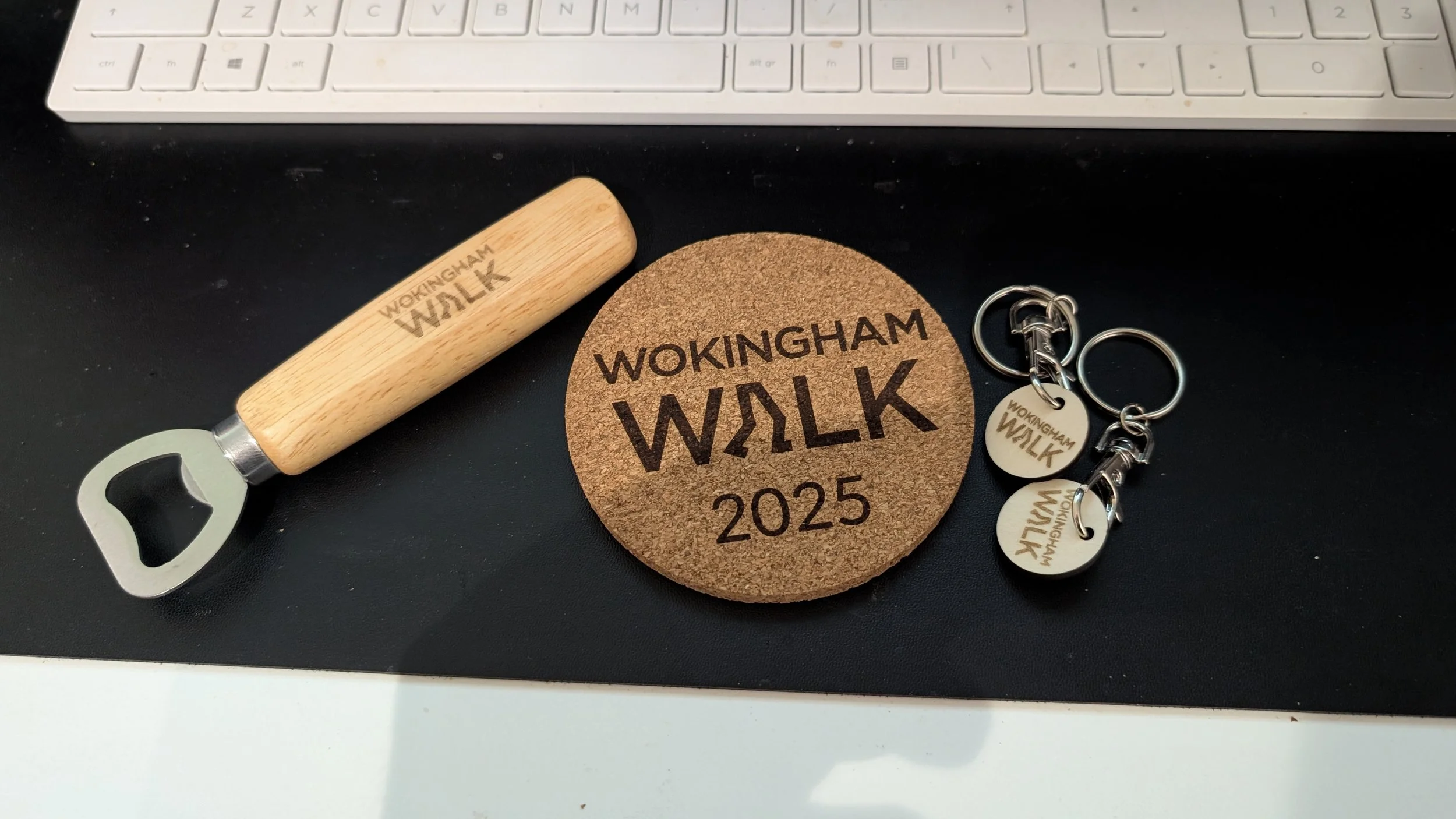 Wokingham Walk 2025 cork coaster, two keyrings and a bottle opener.