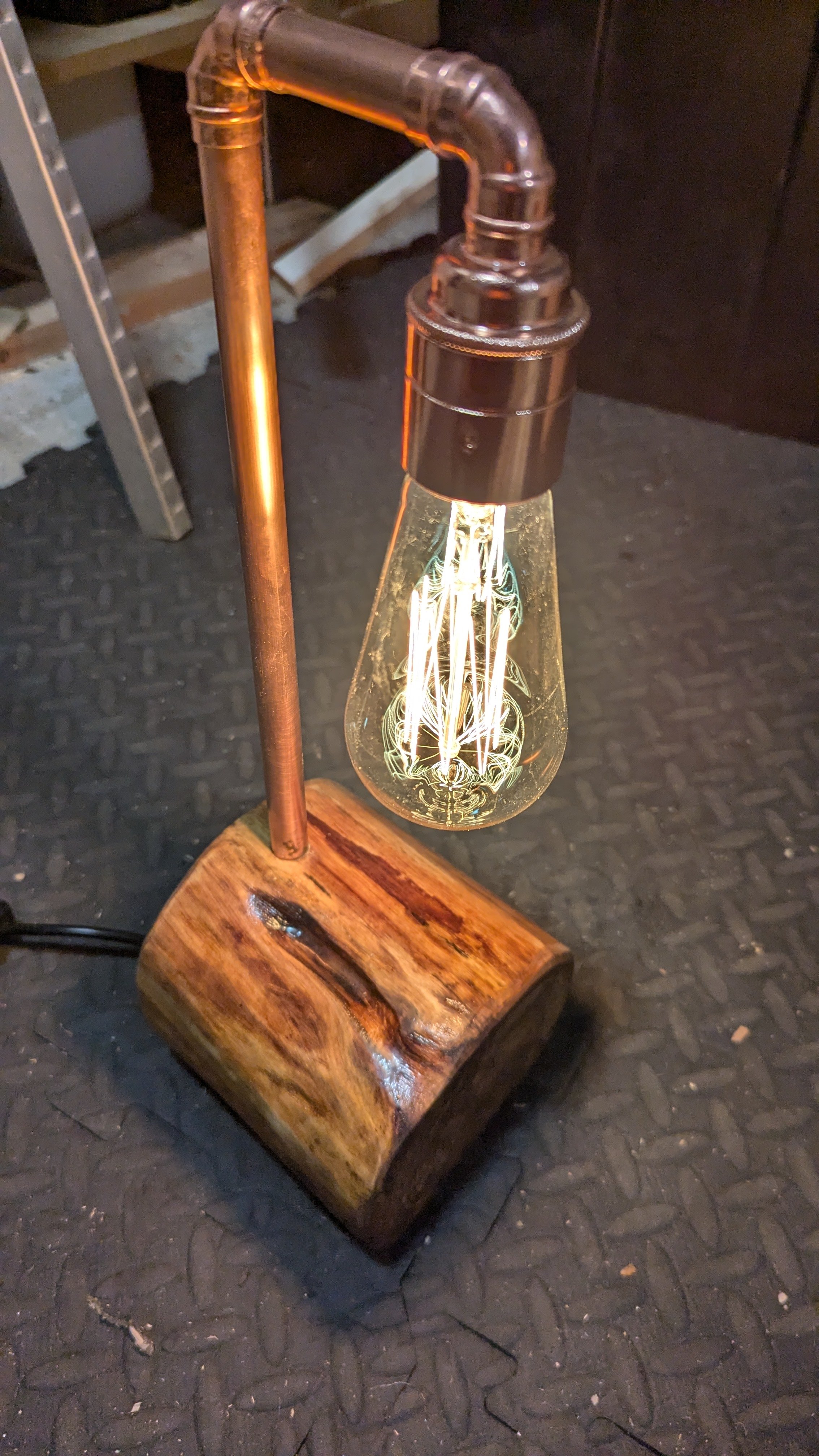 A desk lamp with a vintage-style filament bulb, made from recently felled tree and recycled copper.