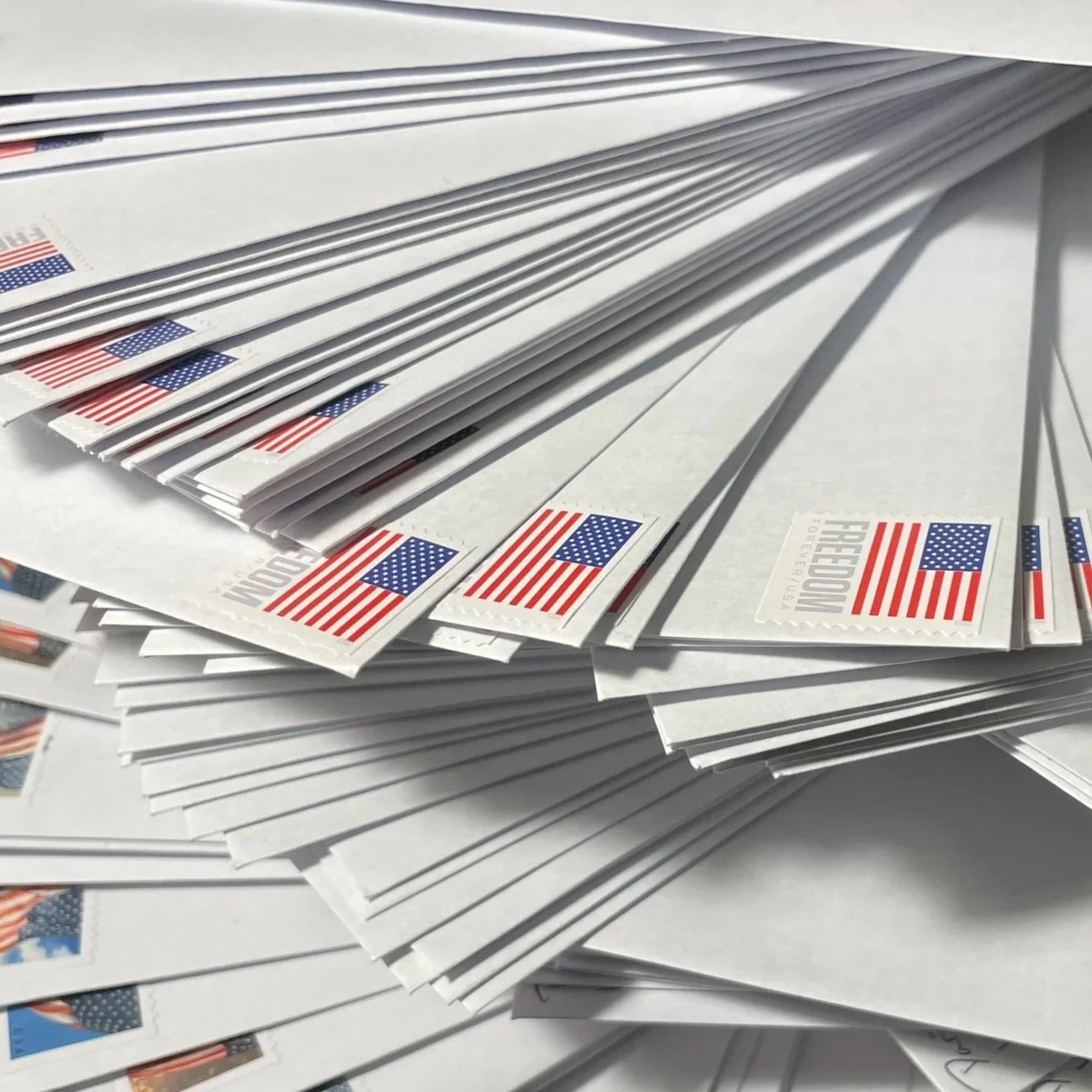 A large stack of stamped envelopes. The stamps depict an American flag.
