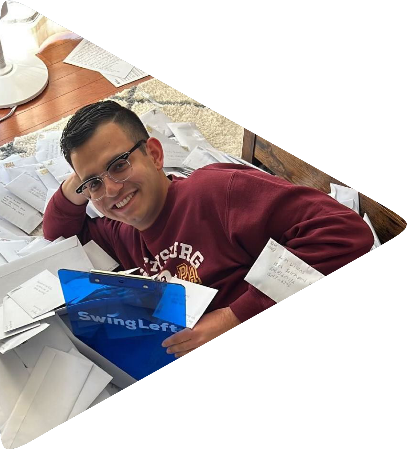 A young man holding a Swing Left clipboard lays on the floor surrounded by letters.