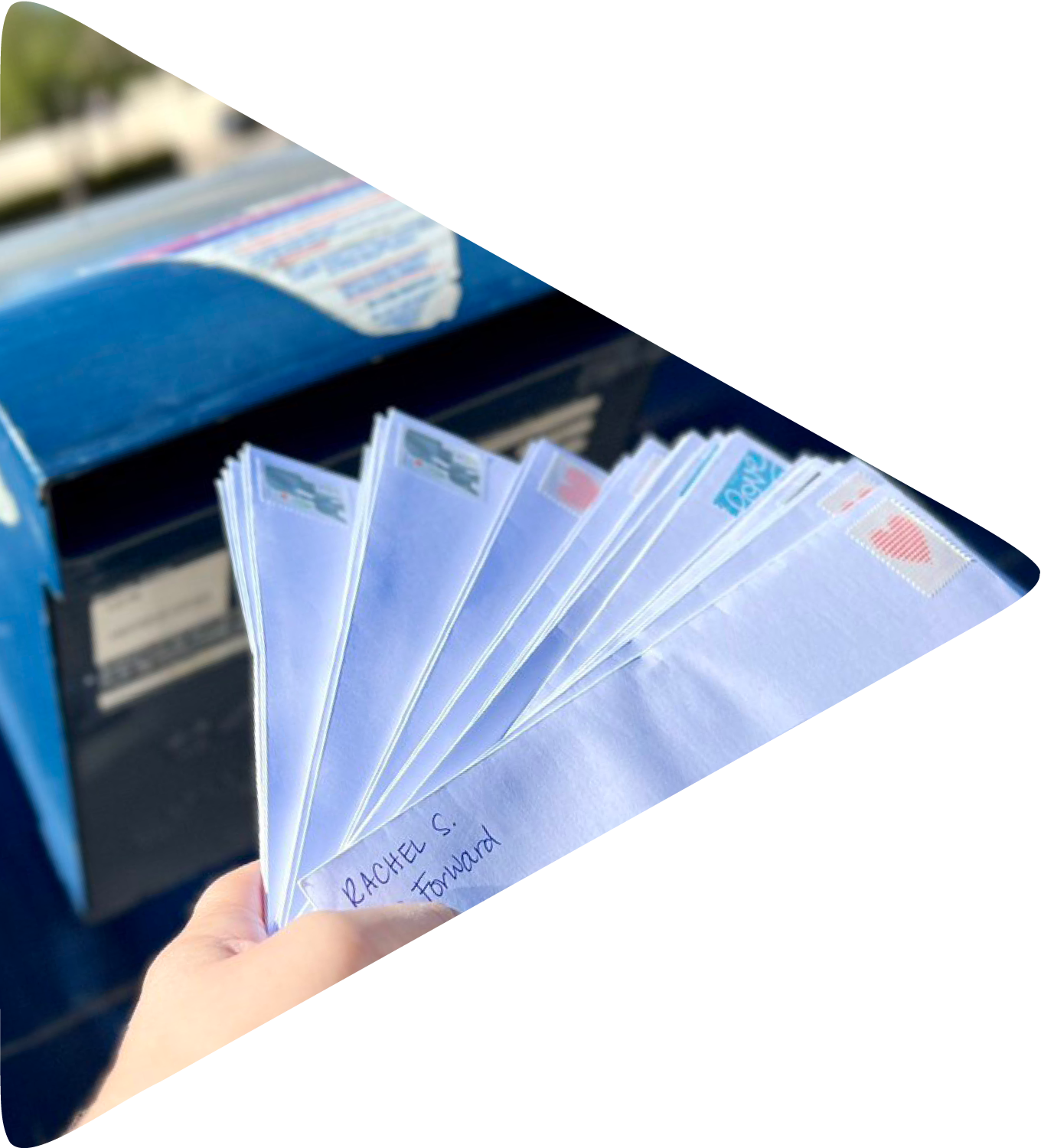 Letters being placed into a blue USPS mailbox.