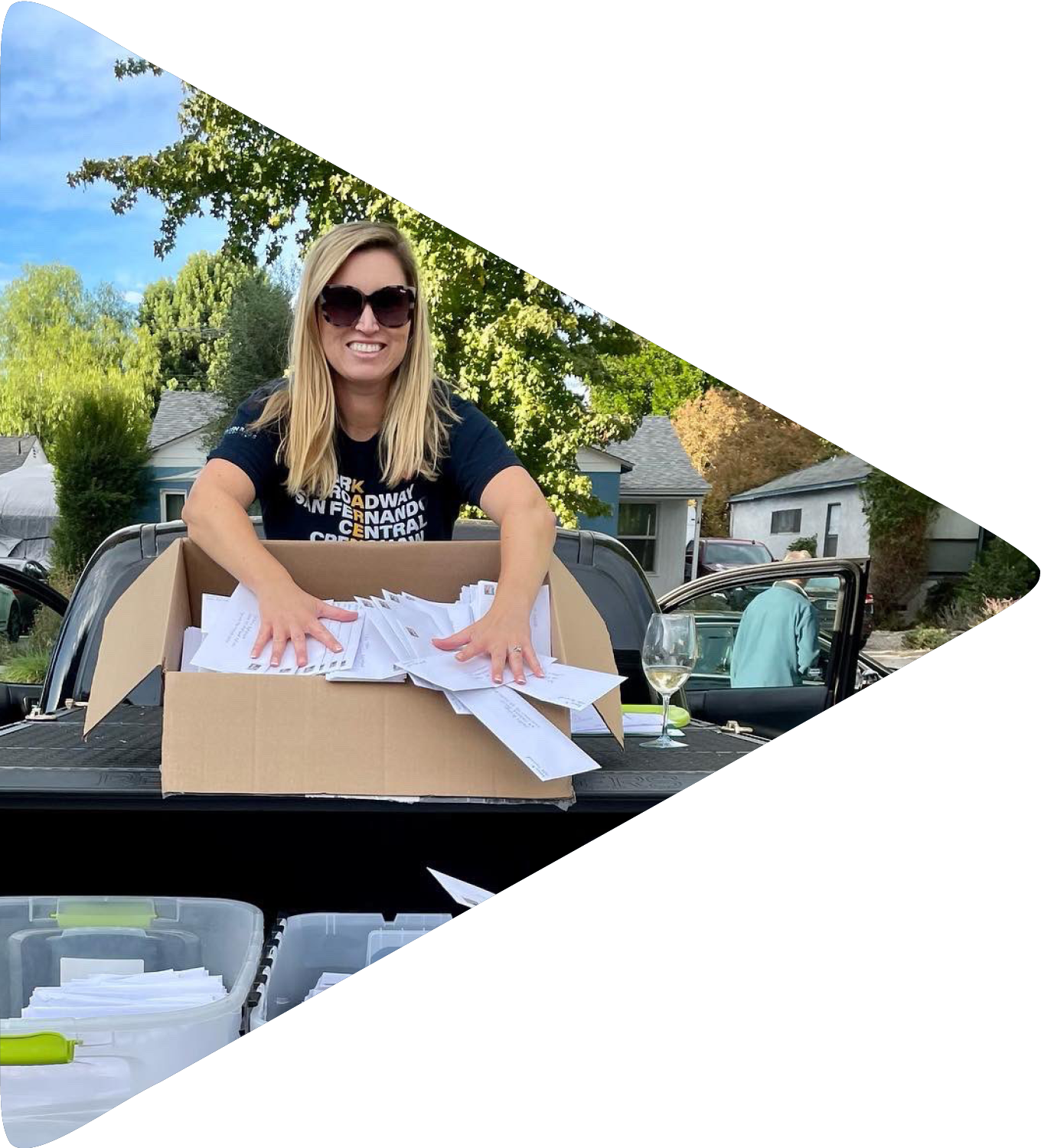A woman sits in the trunk of her car surrounded by boxes of letters.