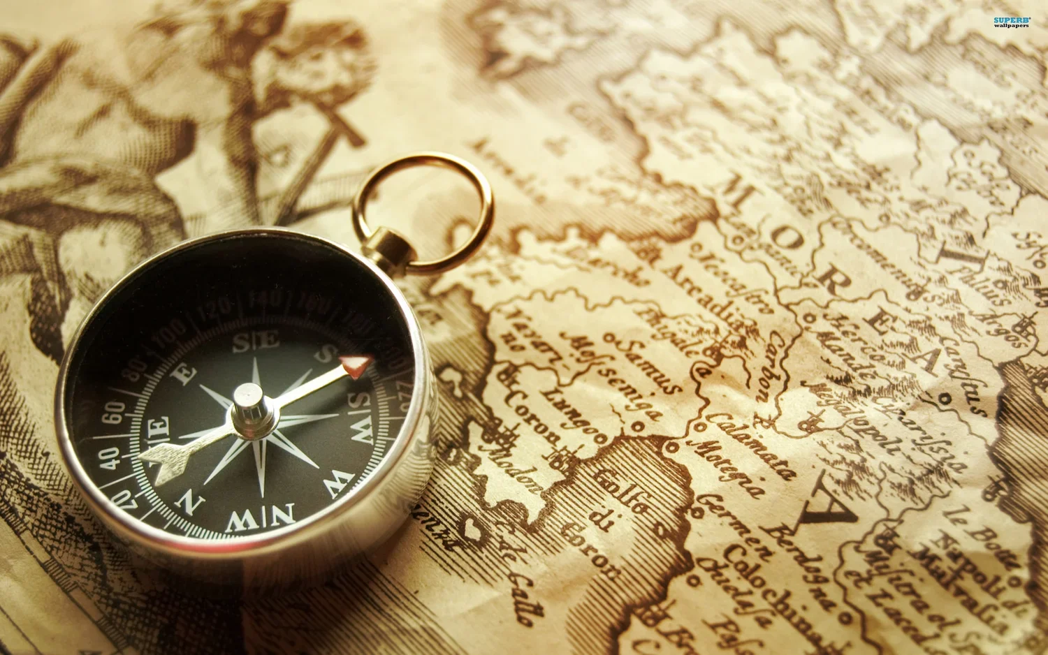 A vintage compass resting on an old, detailed map showing parts of Europe, including France, Germany, and Italy.