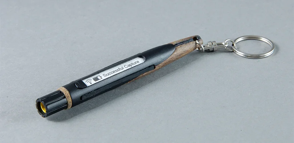 A keychain with a miniature pen designed to look like a wooden pencil, with a small message reading 'Successful Capture' visible on the side.