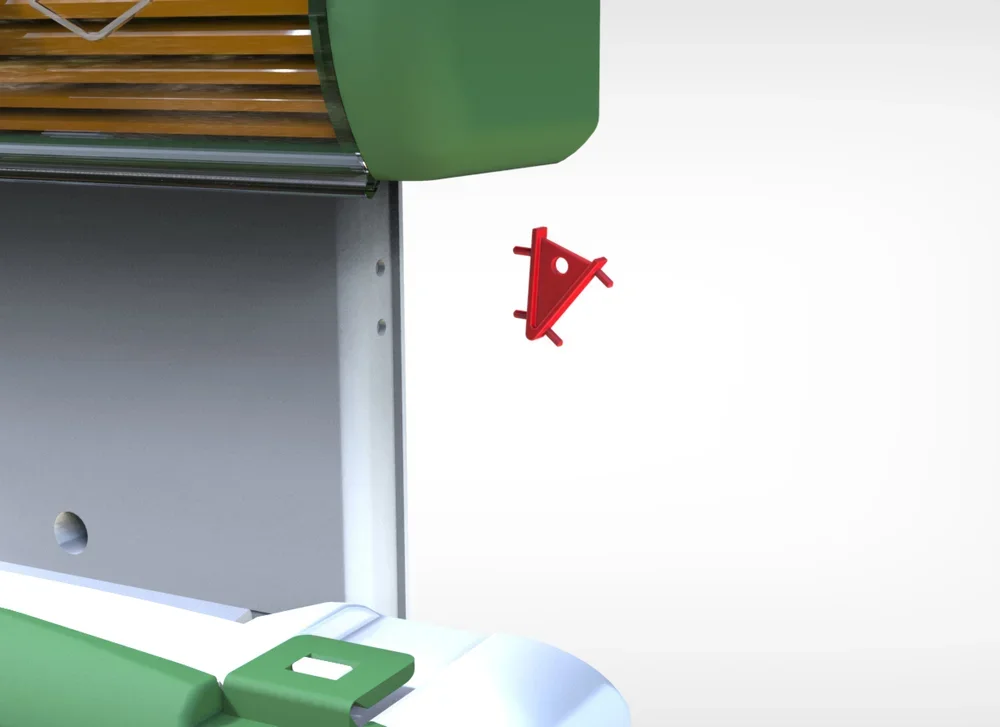 Close-up of a piece of machinery with a green cover, a red triangular safety lock, and metal components.