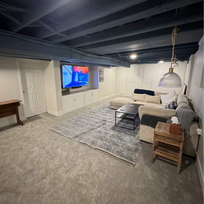 Basement interior with updated carpeting, paint, ceiling, light fixtures, built-ins, and more.