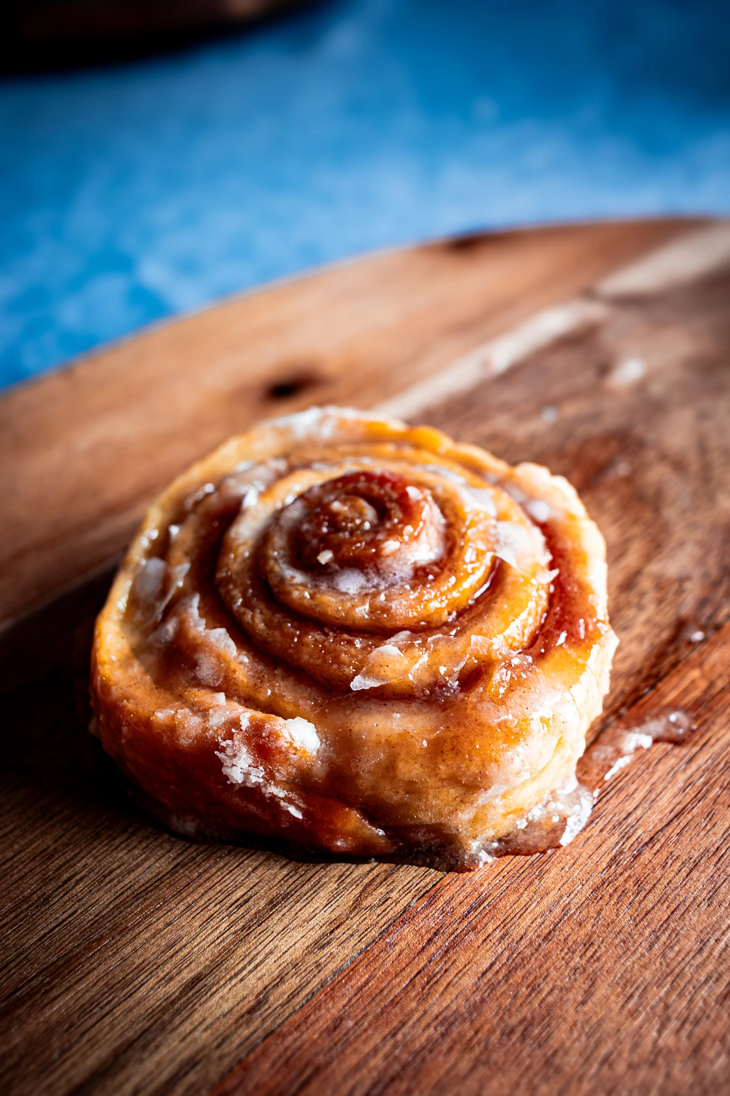 Close-up of a freshly baked cinnamon roll on a wooden table, styled food photography for bakery or cafe marketing in Maryland