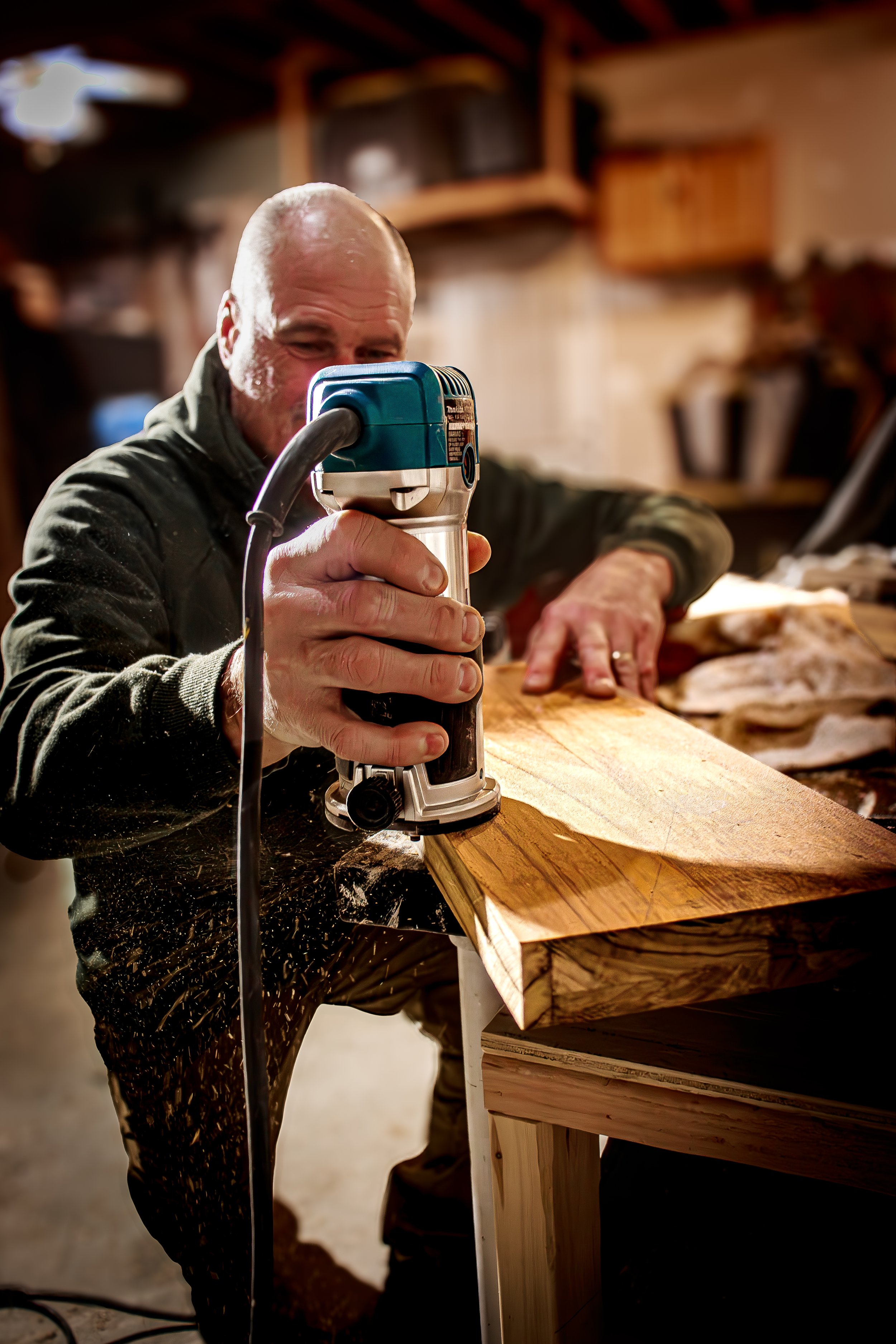 Craftsman working with a handheld saw inside his home workshop. Small business photography showing process of woodworking