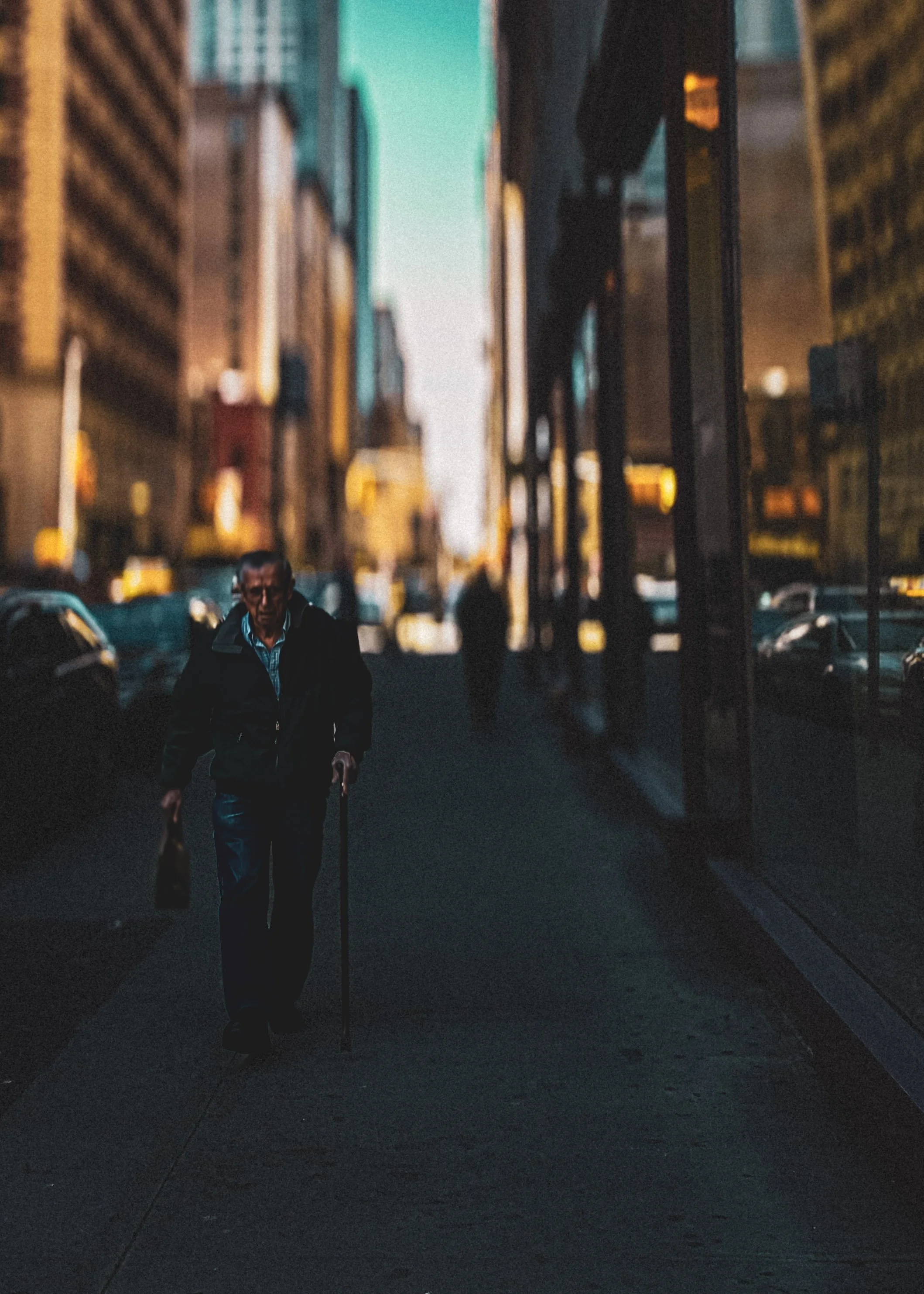 Silhouetted pedestrians walking through a glowing city street at night, framed by tall buildings and warm urban lights.