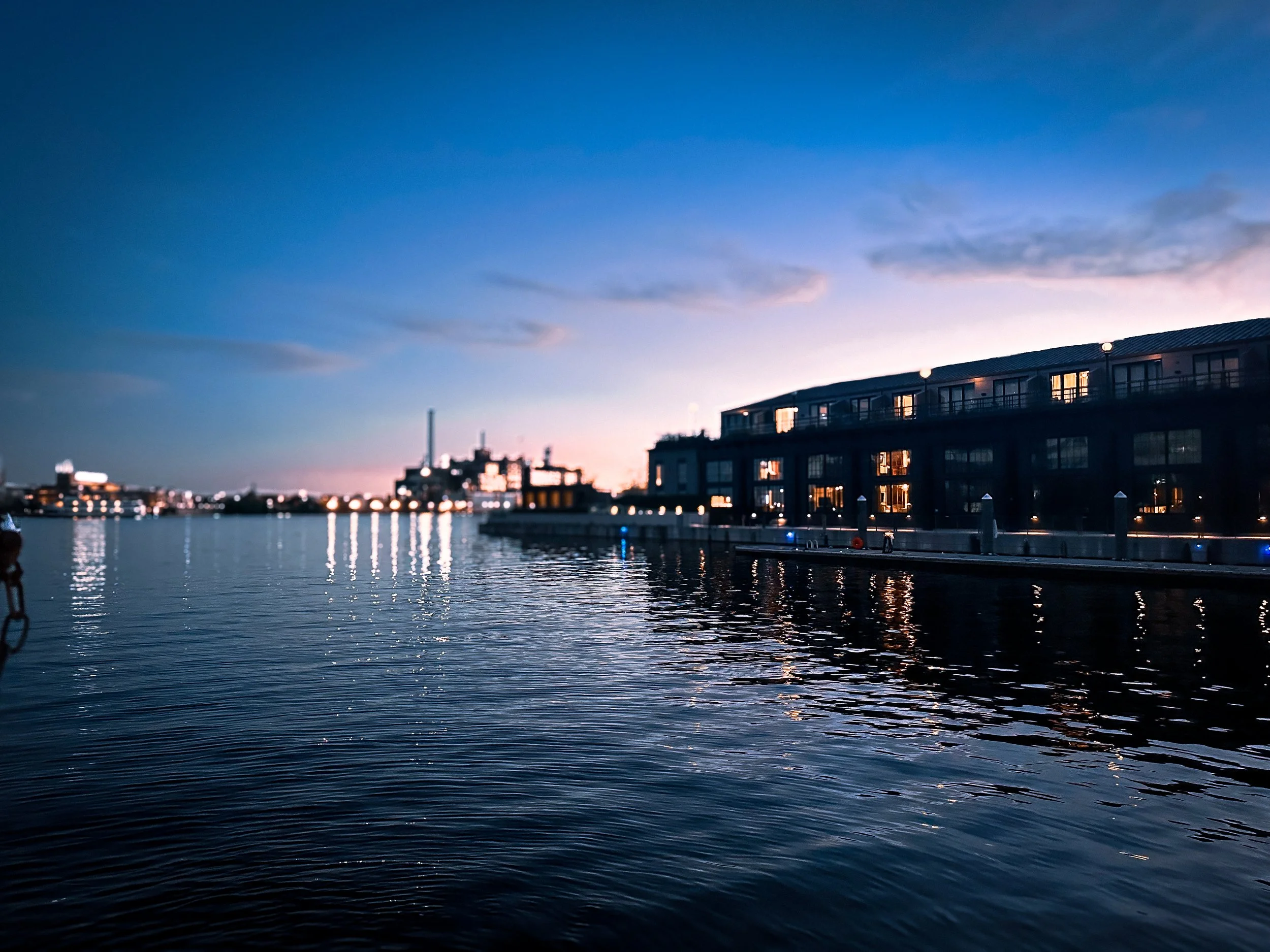 Baltimore Harbor waterfront at dusk with city lights reflecting on the water, photographed by Amy Hood Captures