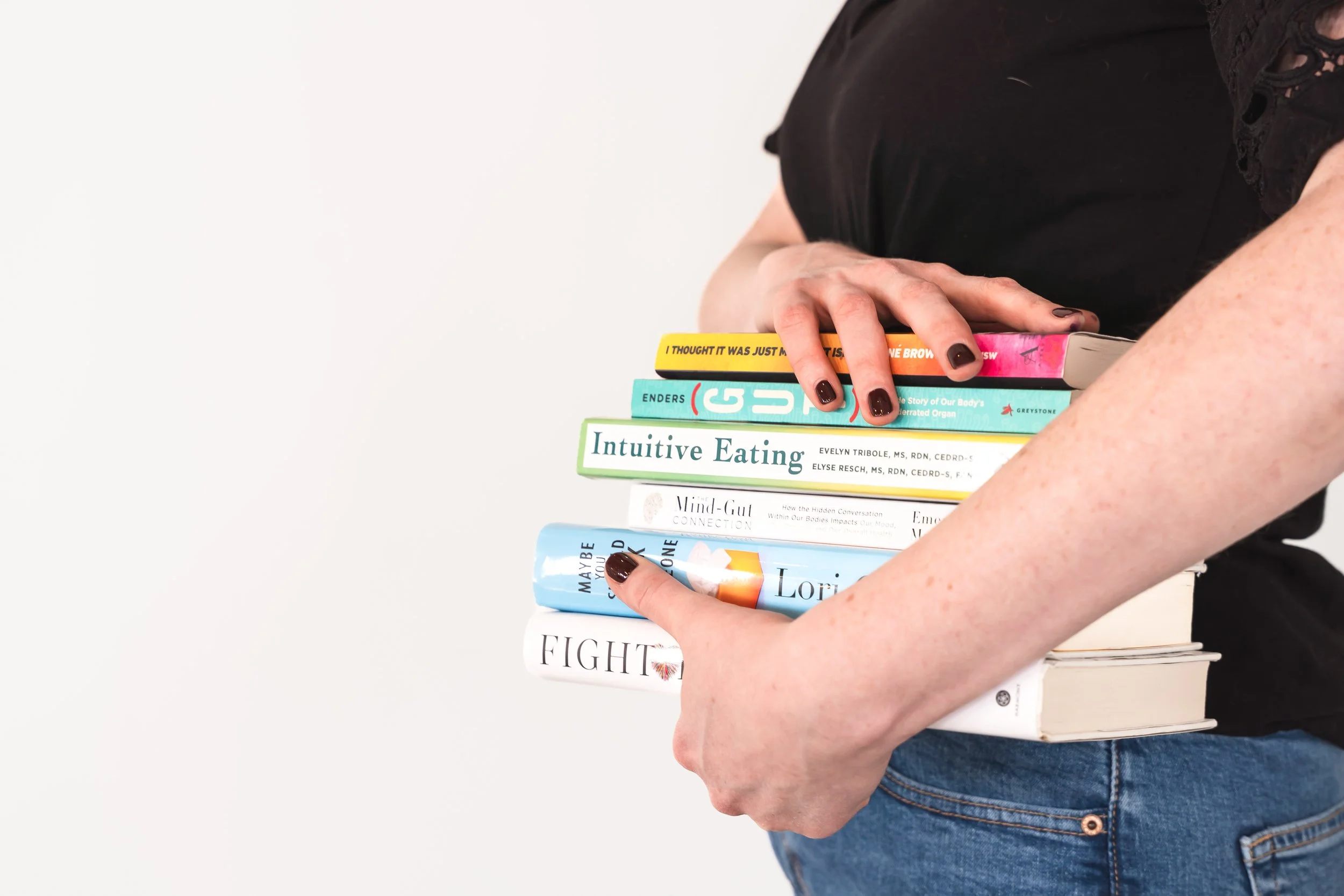 A therapist for disordered eating in Toronto Ontario holding a stack of books about mind-gut connection and intuitive eating