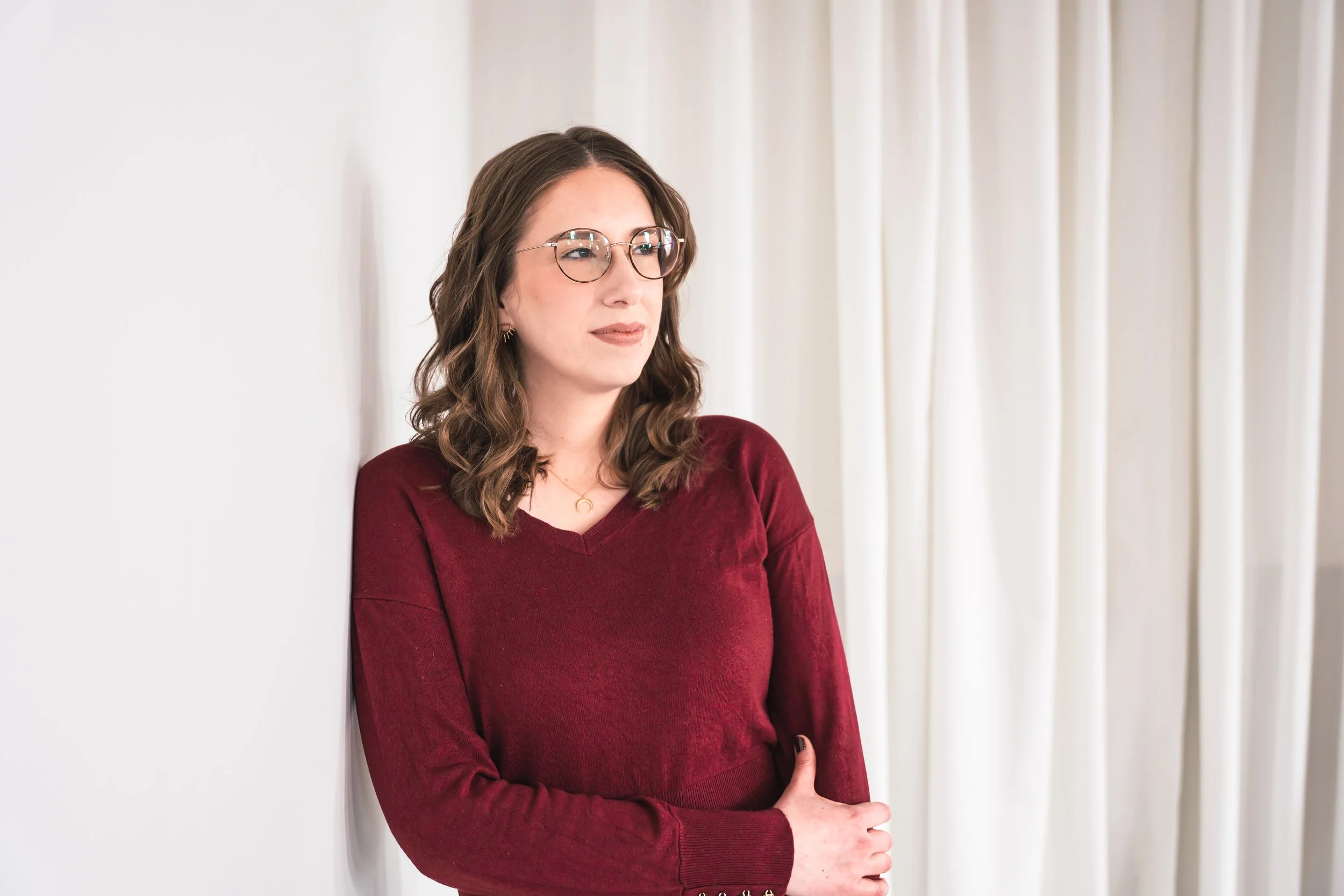 A female Toronto therapist for Colitis anxiety standing against a white white in Ontario.