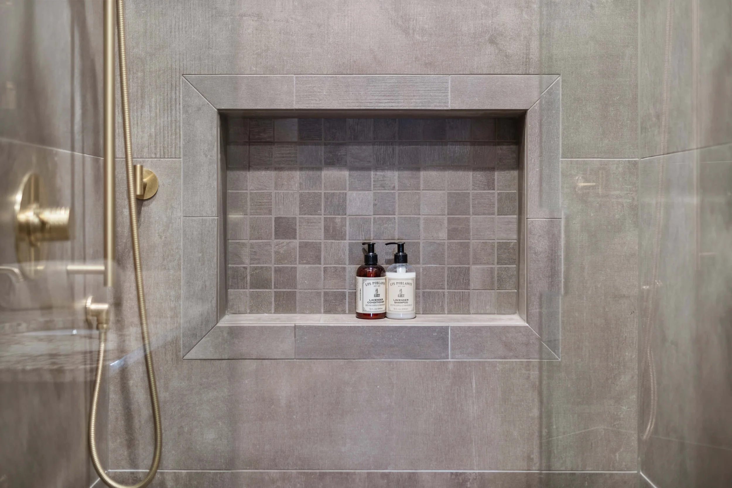 Shower niche with two bottles of Los Poblanos lavender shampoo and conditioner in a tiled shower built by Lakeland Custom Homes..
