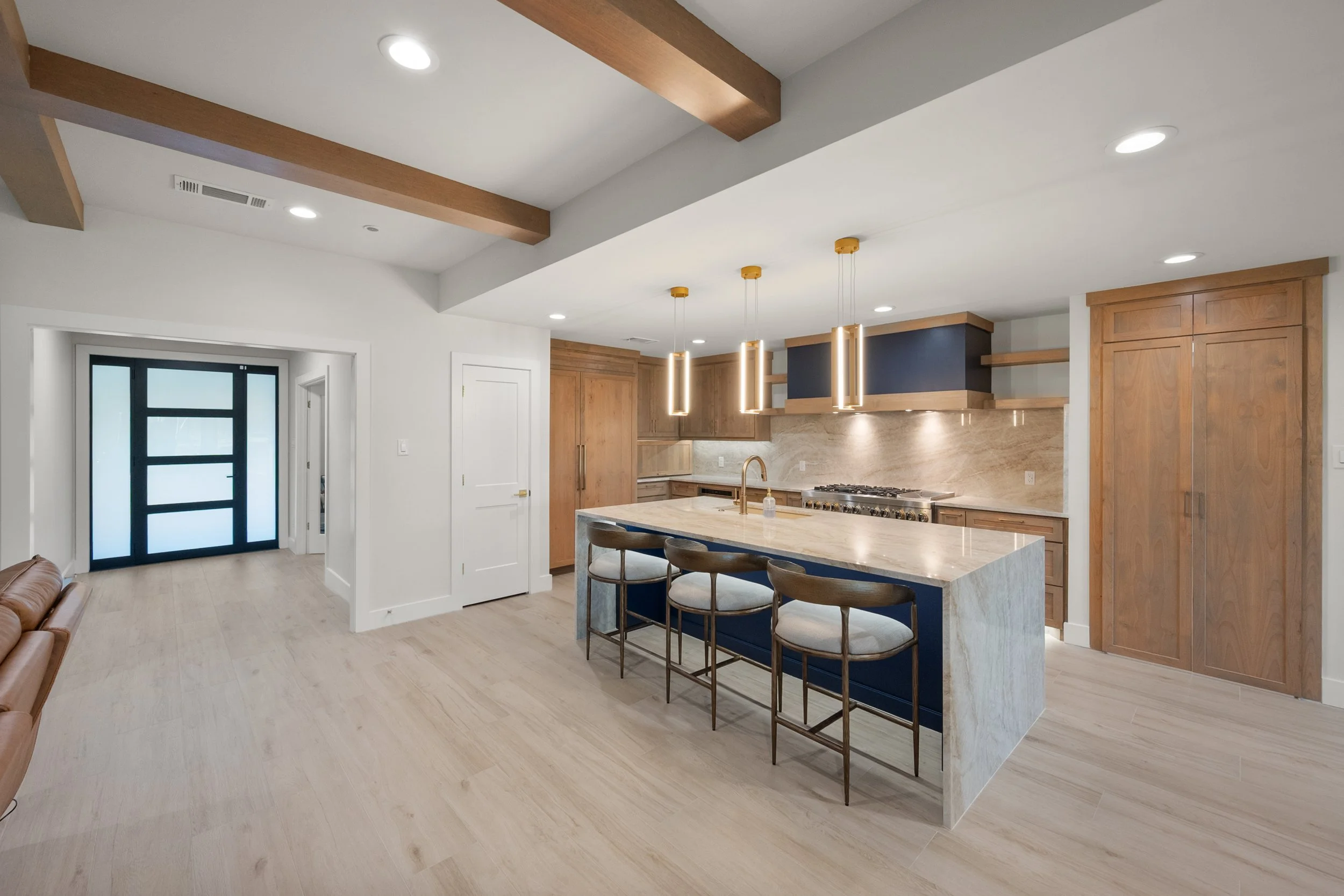 Modern kitchen with wooden cabinets, marble island, and pendant lighting.