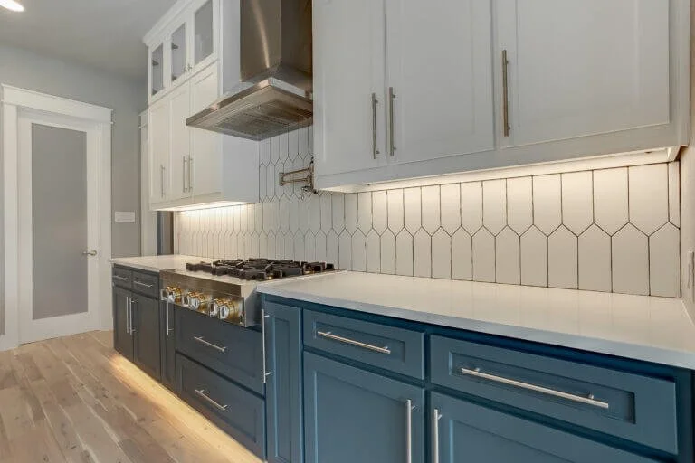 Modern kitchen with blue and white cabinets, tile backsplash, and a gas stove with oven in Mansfield, TX.