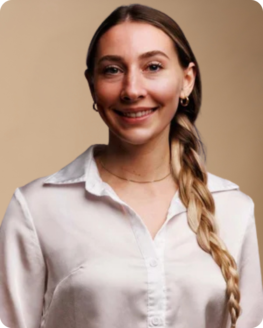 A young woman with long braided hair, wearing a white collared shirt, smiling against a beige background.