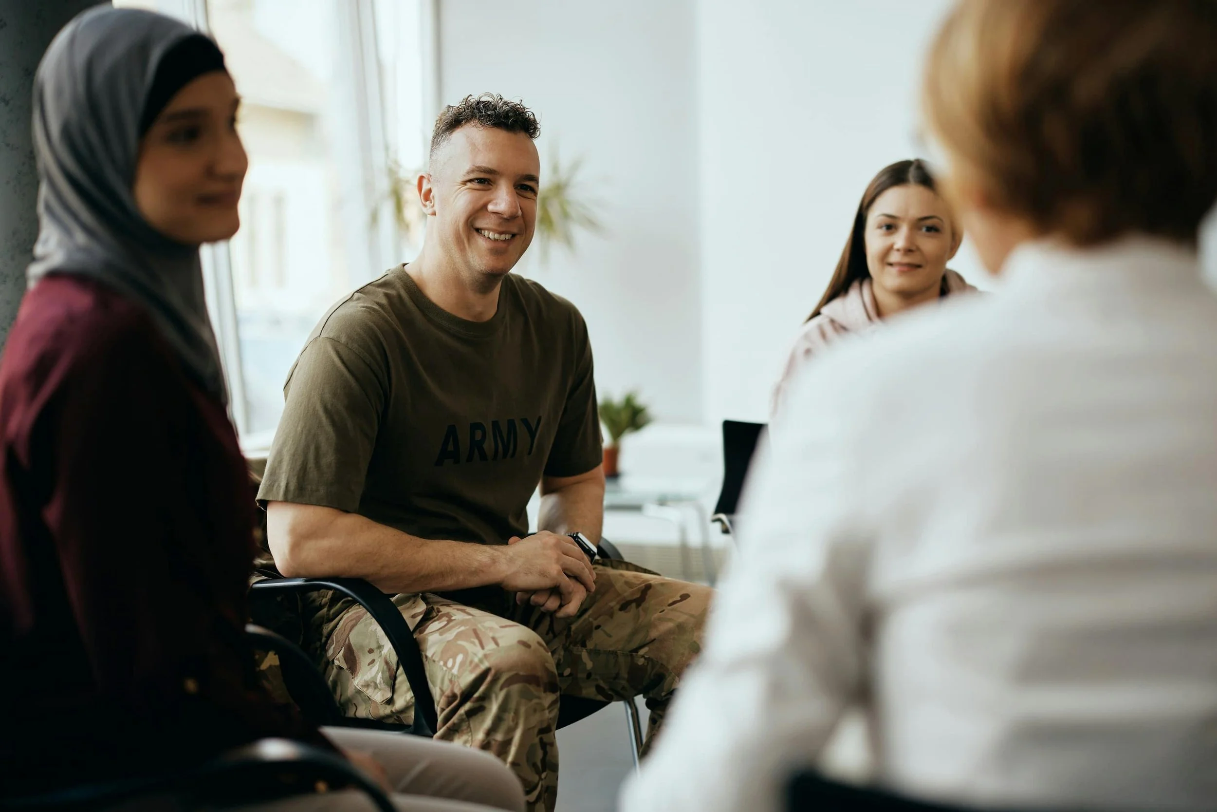 A group of four diverse people sitting in a circle, having a conversation in a well-lit room.