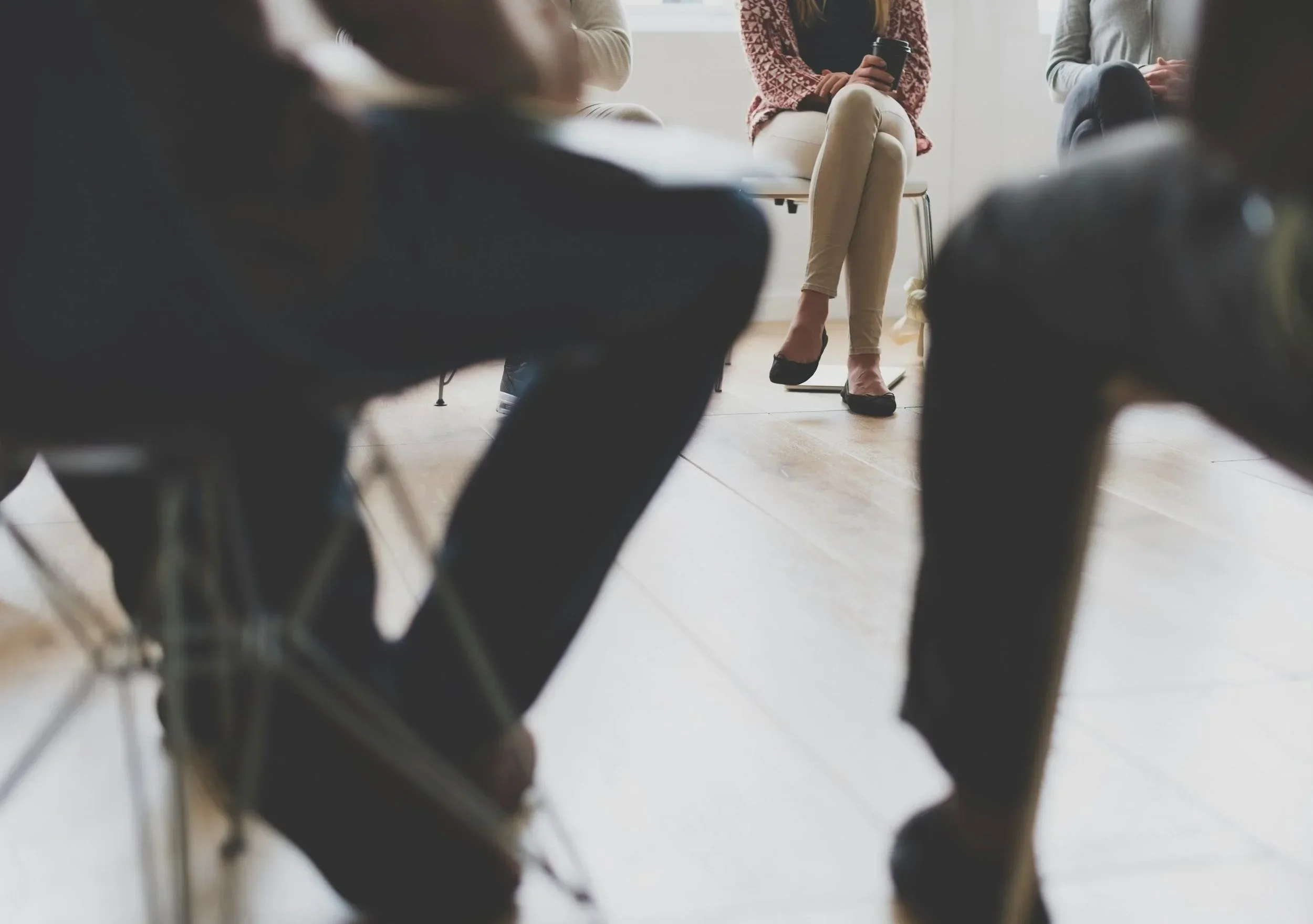 People sitting in a circle during a group discussion with a woman speaking in a professional setting.