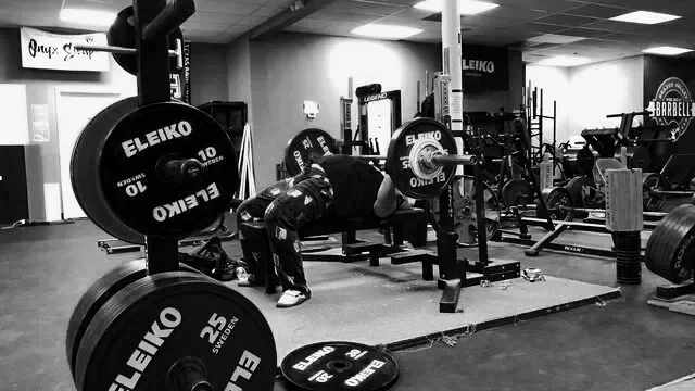 Student doing bench press power lift at Brazos Valley Barbell in College Station Texas