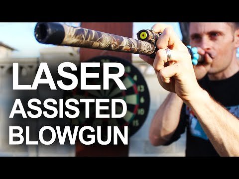 Person aiming a laser-assisted blowgun with camouflage design at a target.