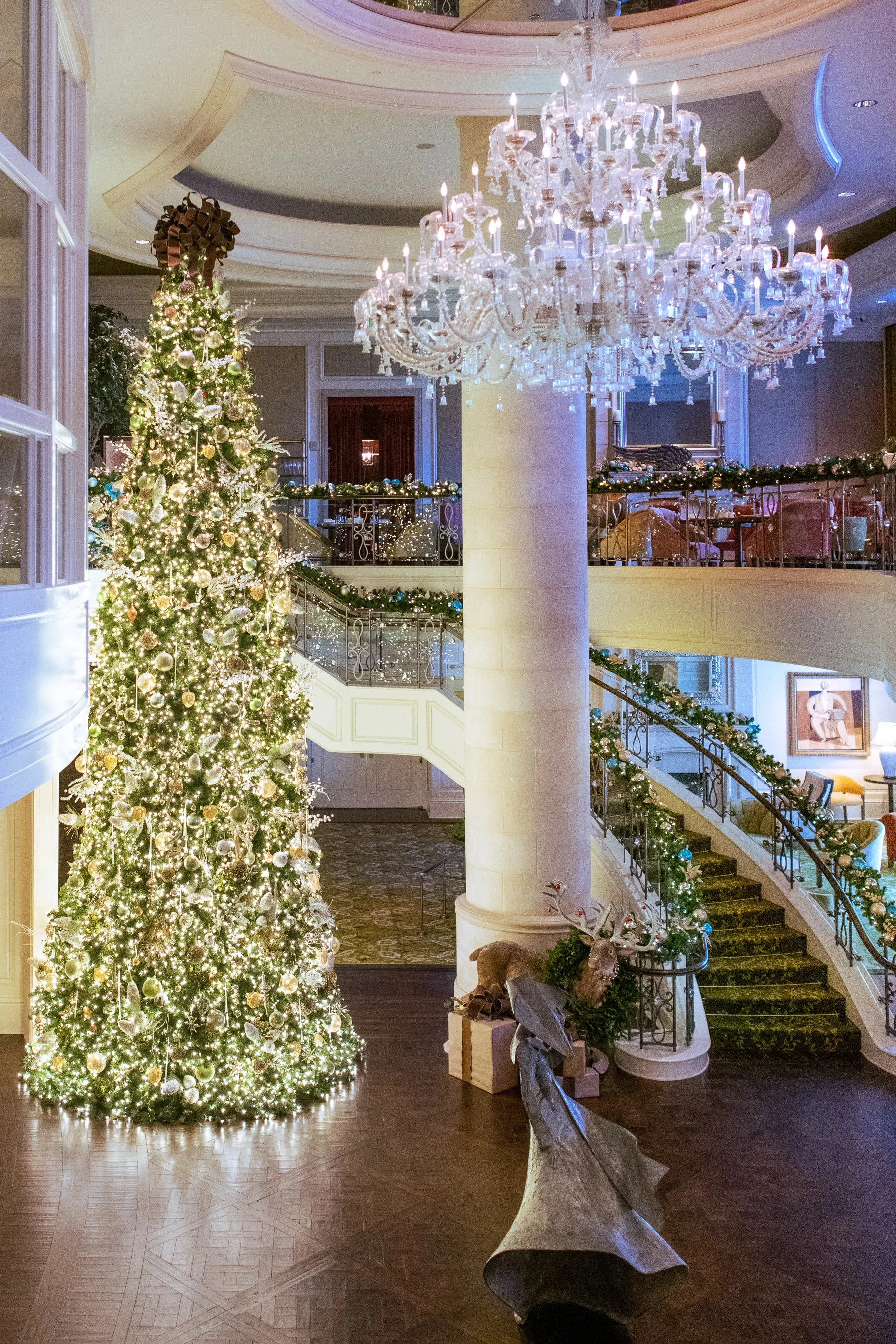 St. Regis Atlanta Tea with Santa and Christmas Decorations. There is a reindeer figure and wrapped presents at the base of the tree.