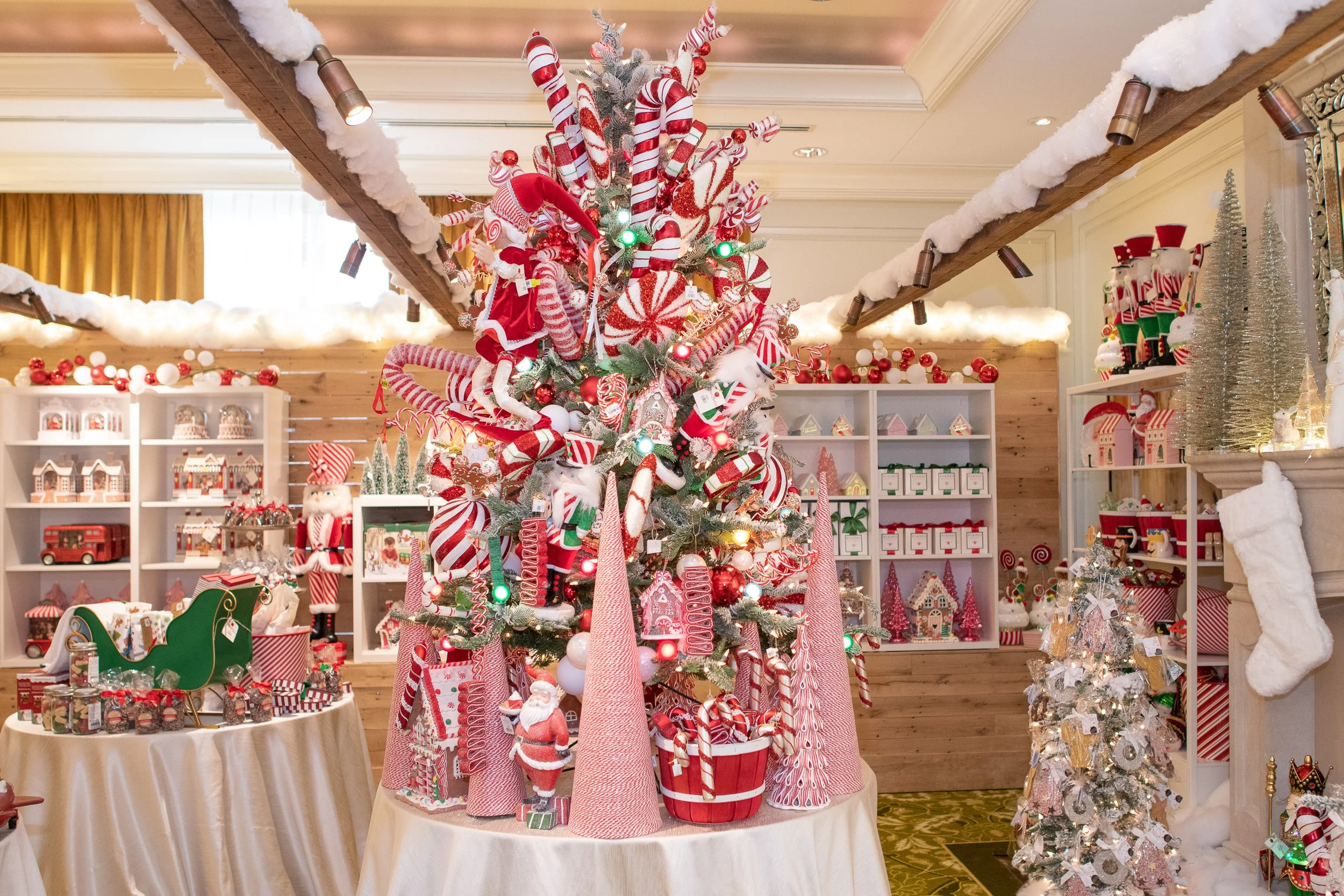 St. Regis Atlanta Christmas Market pop up with Lucy's.  A Christmas display with a decorated tree featuring candy cane ornaments, peppermint swirls, Santa hats, and red and white striped decorations