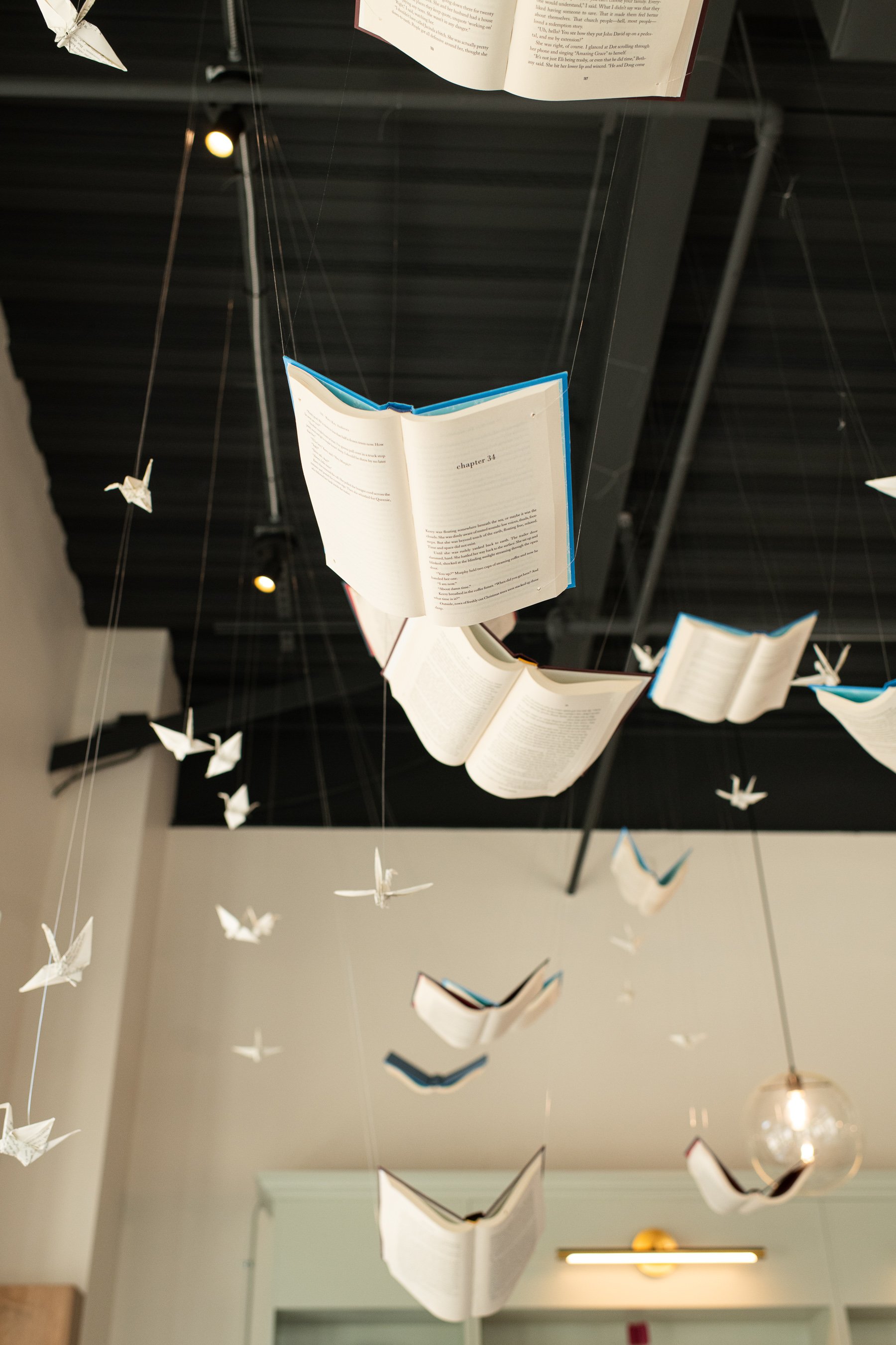 Airplanes made of paper hanging from the ceiling, arranged to resemble birds in flight.
