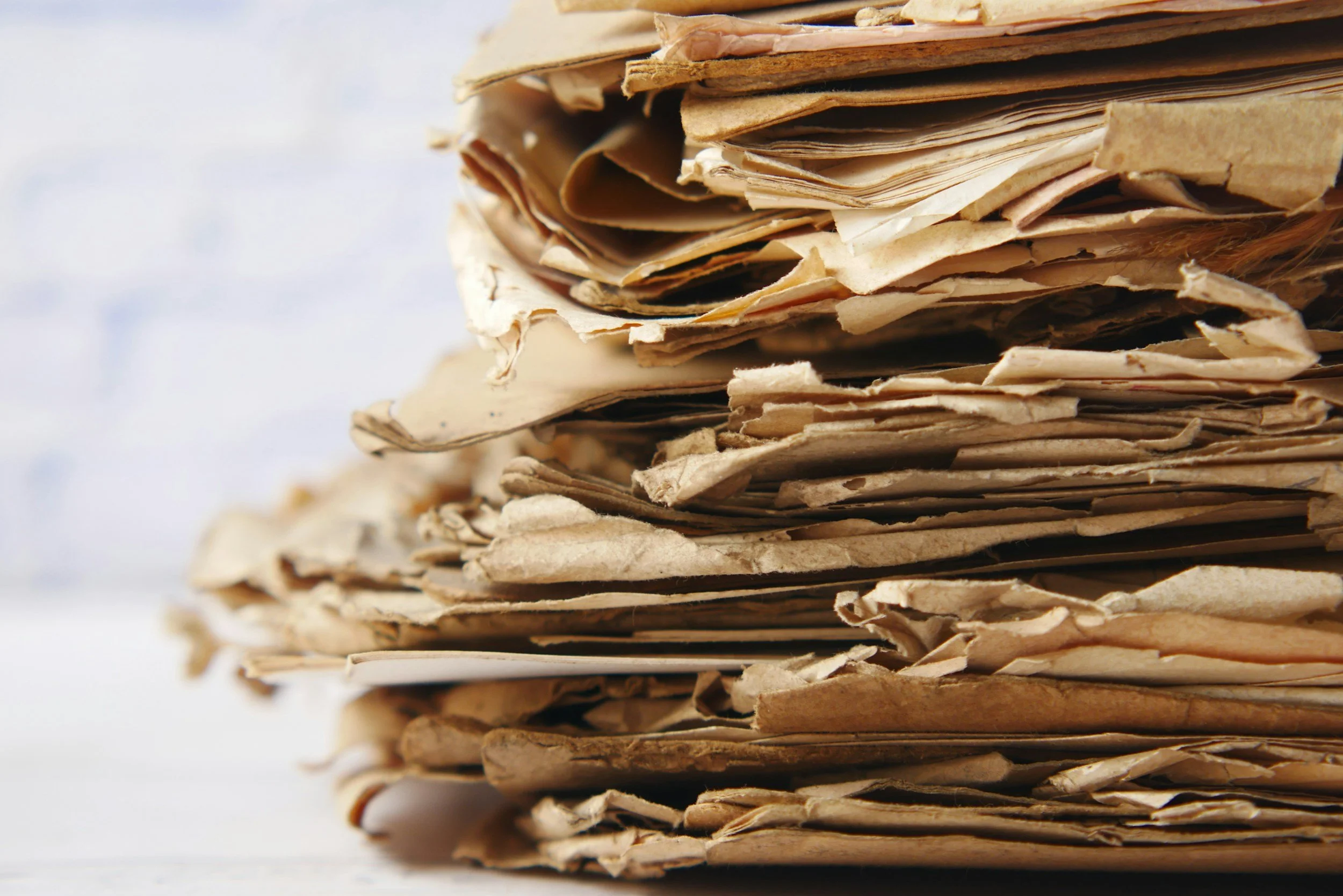 Close-up of a stack of crumpled, aged brown paper or newspapers.