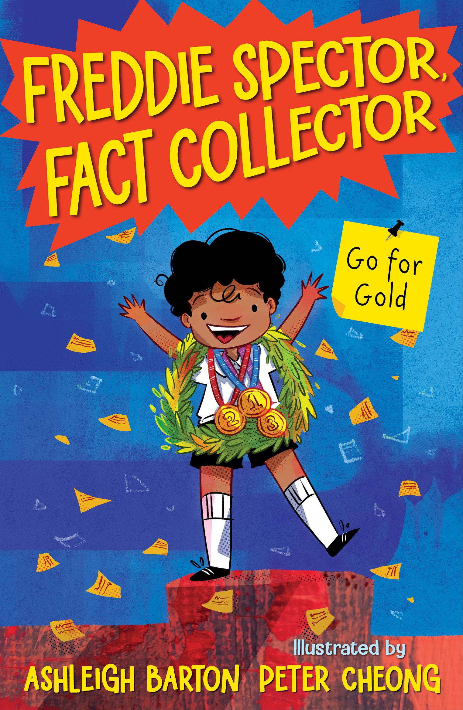 A colorful illustrated book cover featuring a young boy with curly hair and a big smile, wearing a sports uniform with medals, standing on a red podium with a laurel wreath, surrounded by falling papers and confetti, with bold yellow and red text that reads 'Freddie Spector, Fact Collector' and a yellow note that says 'Go for Gold'.