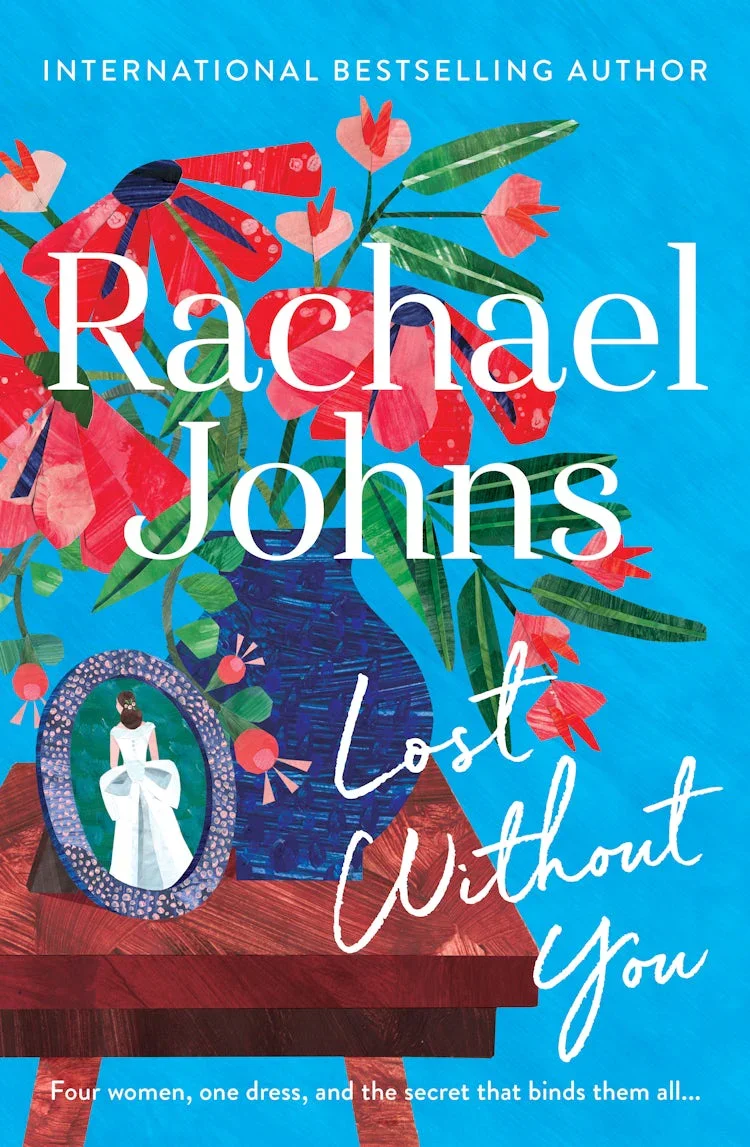 Book cover titled "Lost Without You" by Rachel Johns, featuring a colorful illustration of a blue vase with pink flowers on a wooden table, a framed portrait of a woman in a white dress, and background in shades of blue.