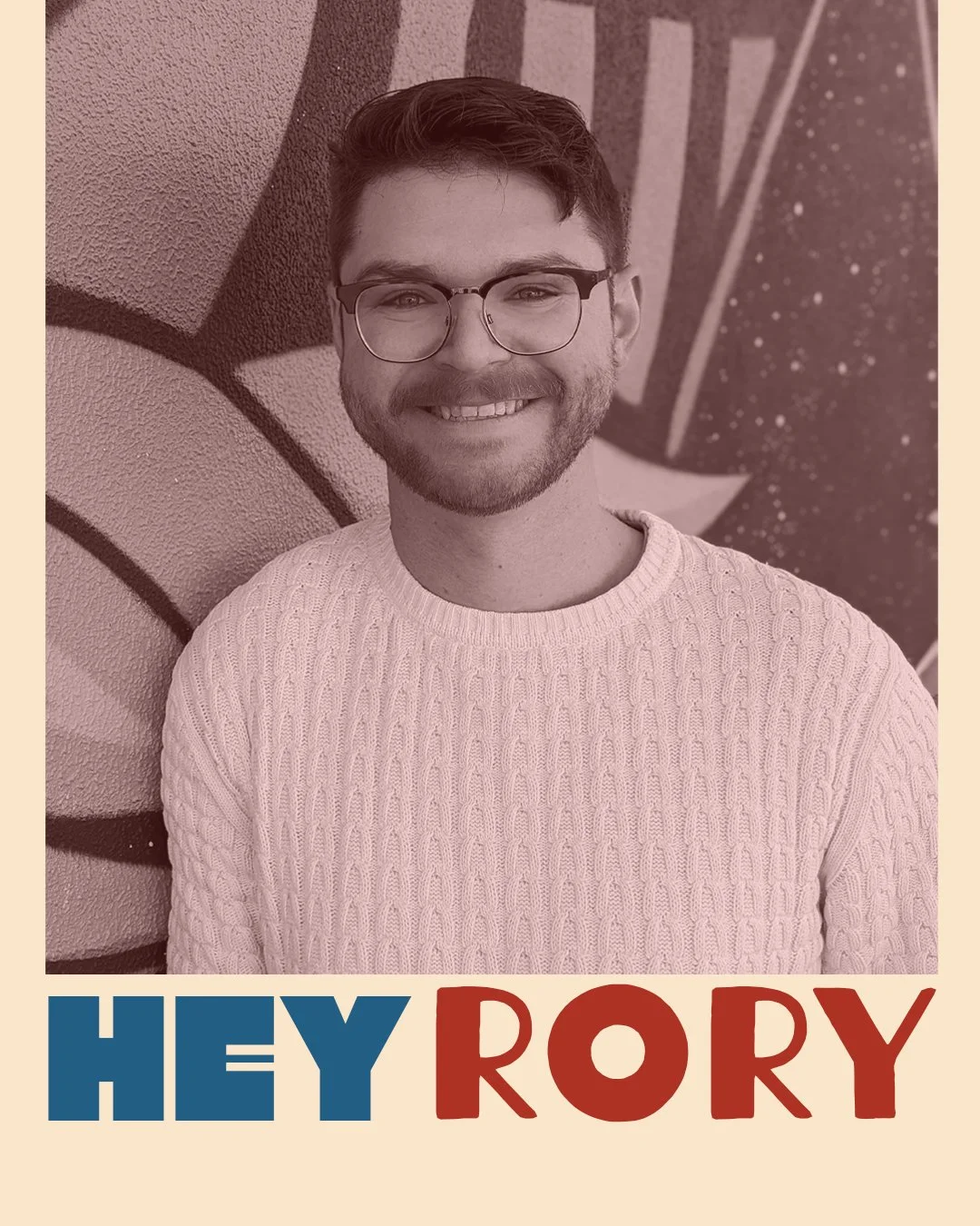 A young man with glasses and a beard smiles while standing in front of a graffiti wall. The image has a pinkish tint, with the words "HEY RORY" in bold blue and red letters at the bottom.